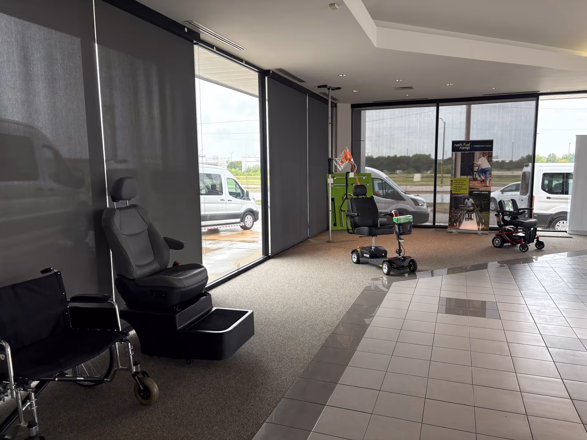 Interior showroom with mobility scooters and a wheelchair near large windows.