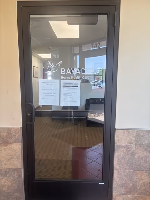 Glass door displays BAYADA Home Health Care logo, opening to a lobby with posted notices.