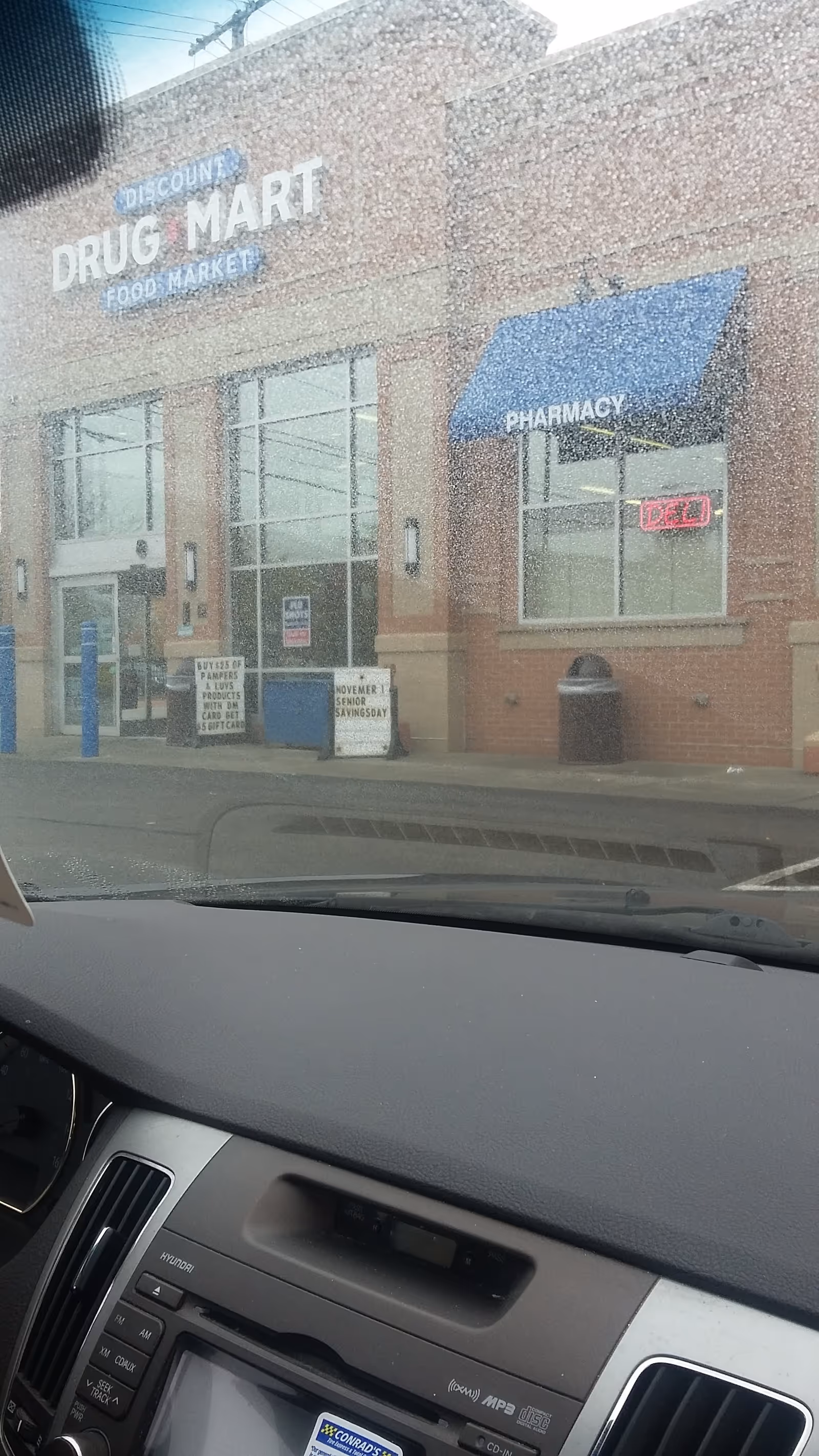 Exterior view of Discount Drug Mart storefront with pharmacy sign and blue awning.