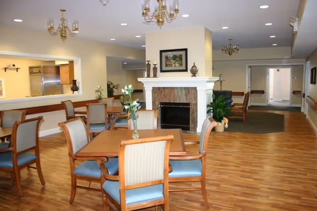 Woodlands at Hampton Woods common area with tables, chairs, fireplace, and plants
