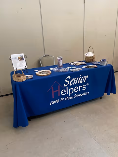 Indoor display table with Senior Helpers branding and brochures on a blue tablecloth