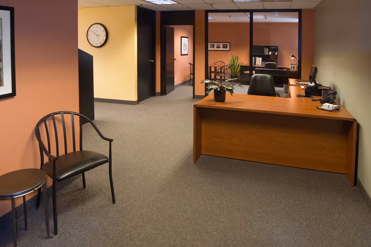 Reception desk in a quiet office lobby with chairs and partitioned offices.