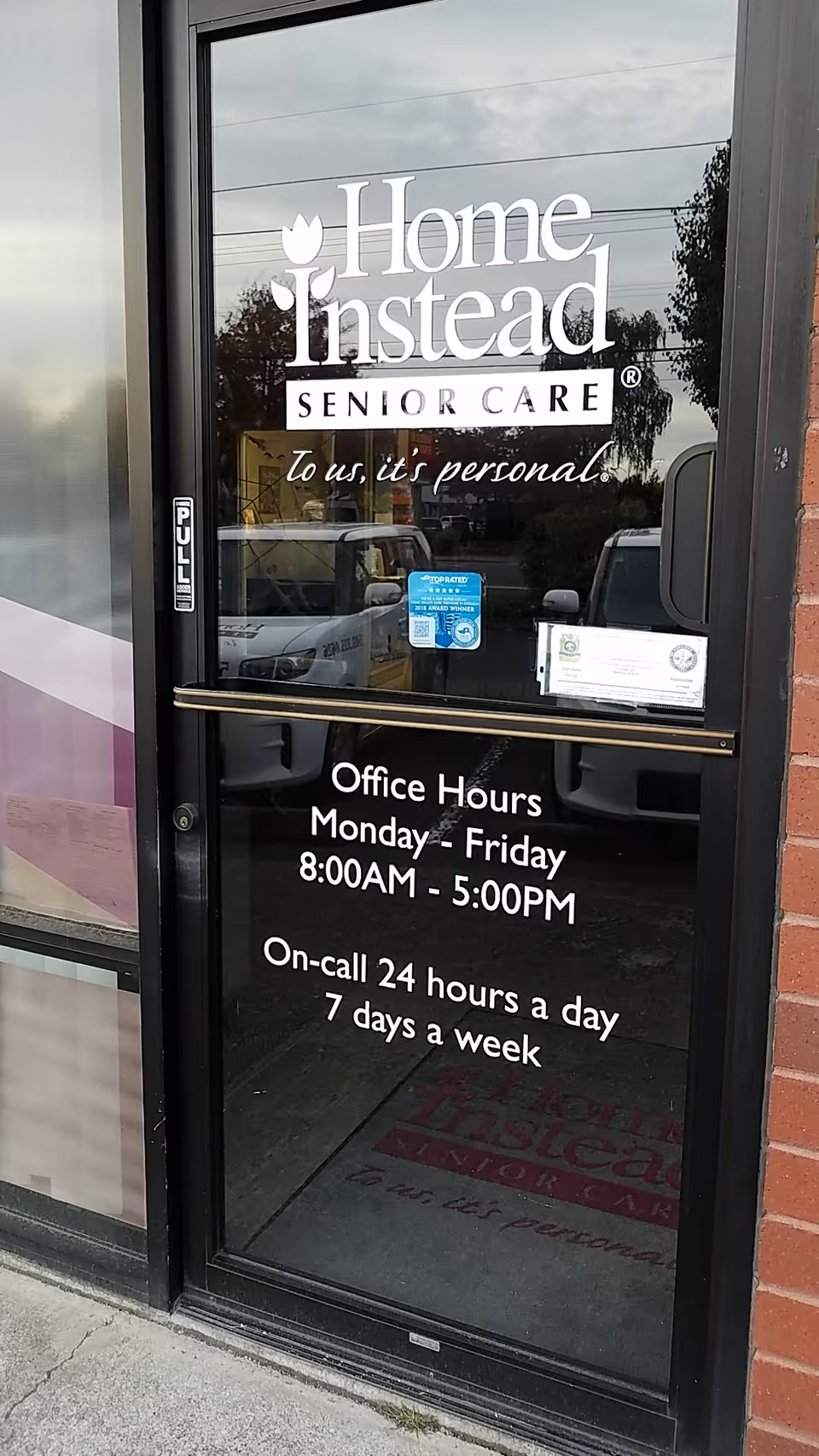 Glass door shows Home Instead Senior Care logo and office hours at the entrance.