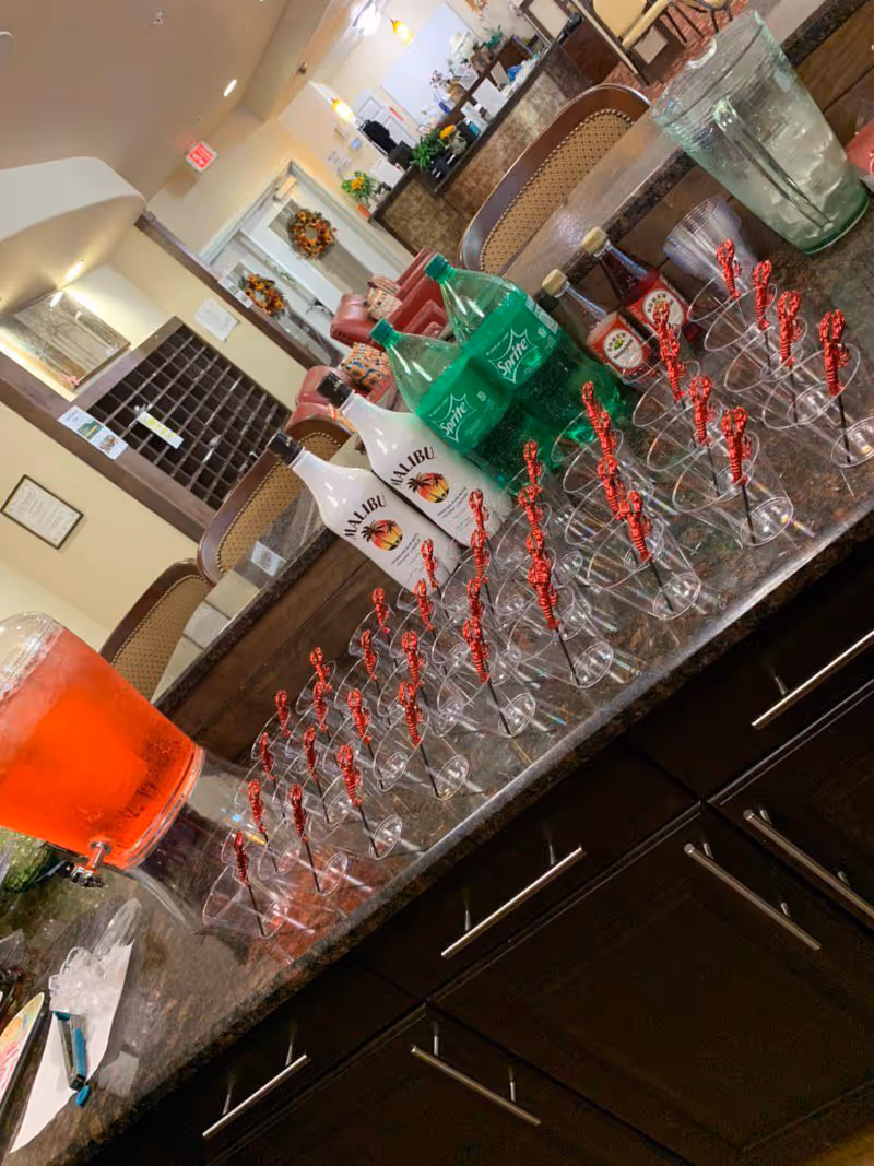 Indoor lounge area with a long counter displaying Malibu and Sprite bottles and glassware.