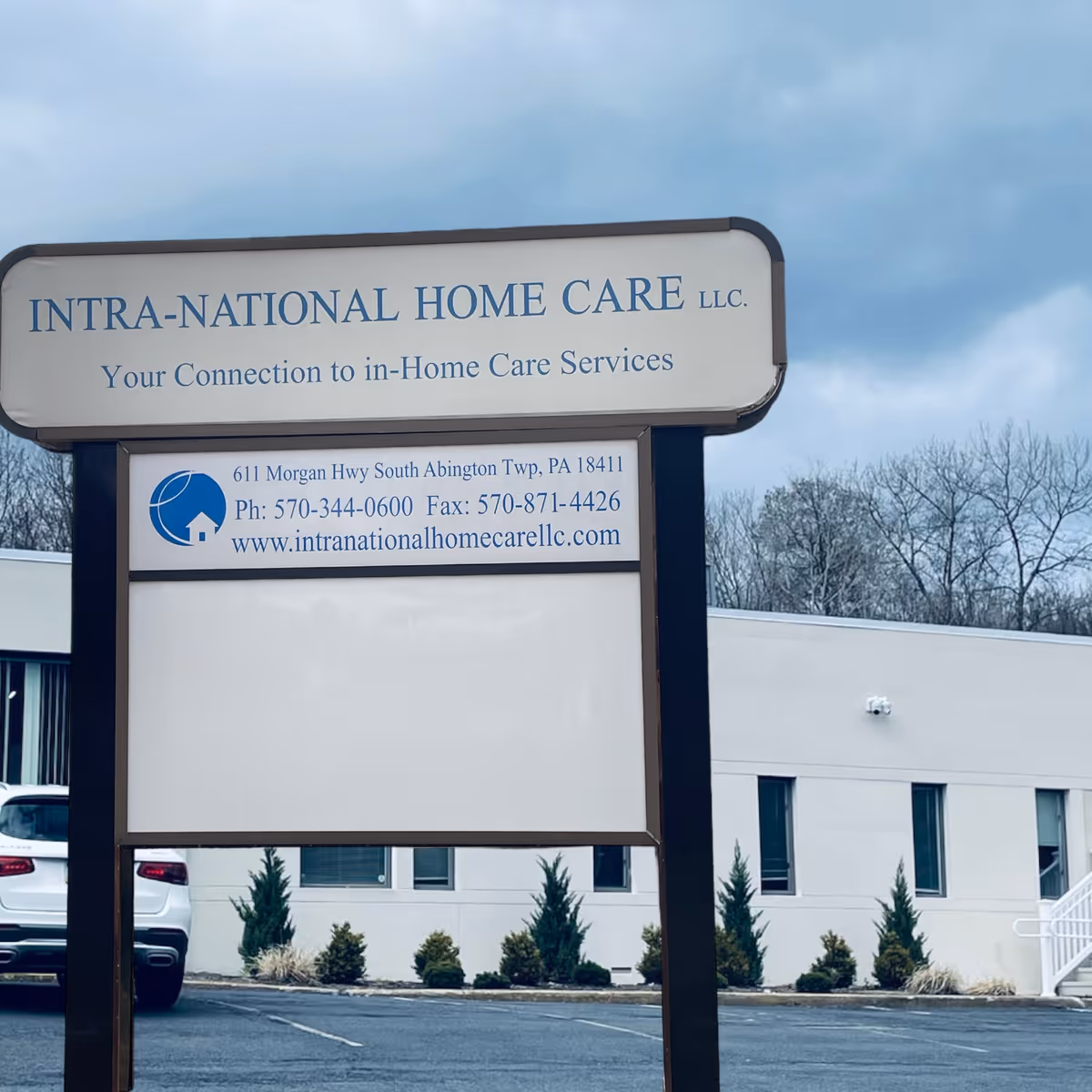 Outdoor sign reads INTRA-NATIONAL HOME CARE LLC with building and bare trees behind.