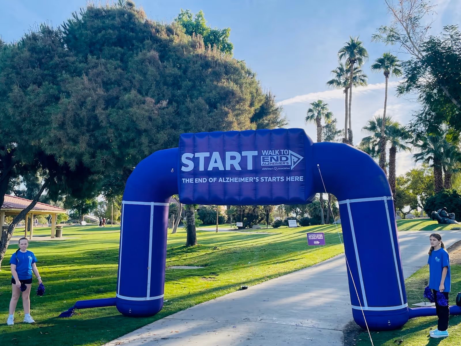 Blue inflatable start arch for Alzheimer's walk in a sunlit park with volunteers