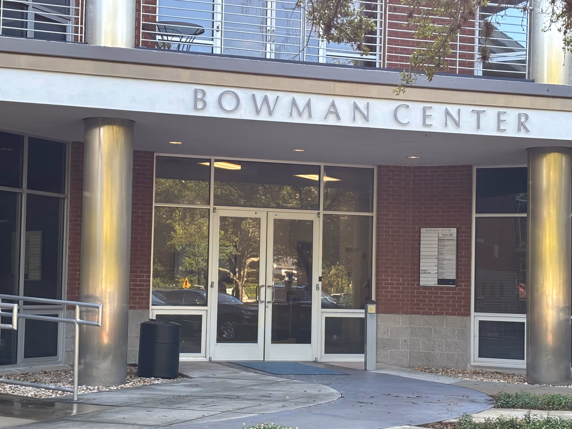 Front entrance of a brick building with glass doors and large columns.