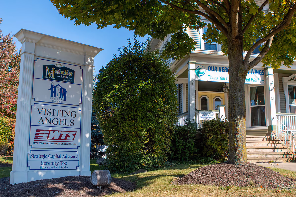 Front exterior of a building with Visiting Angels signage and a tall multi-tenant sign.
