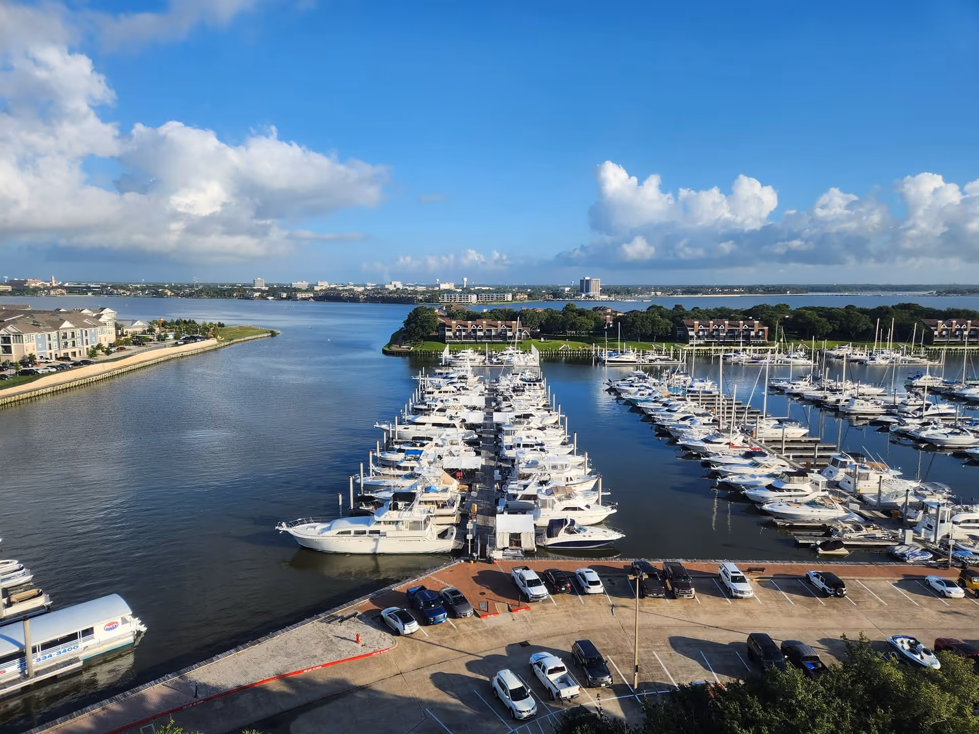 Aerial view of a marina with rows of docked boats and nearby parking.