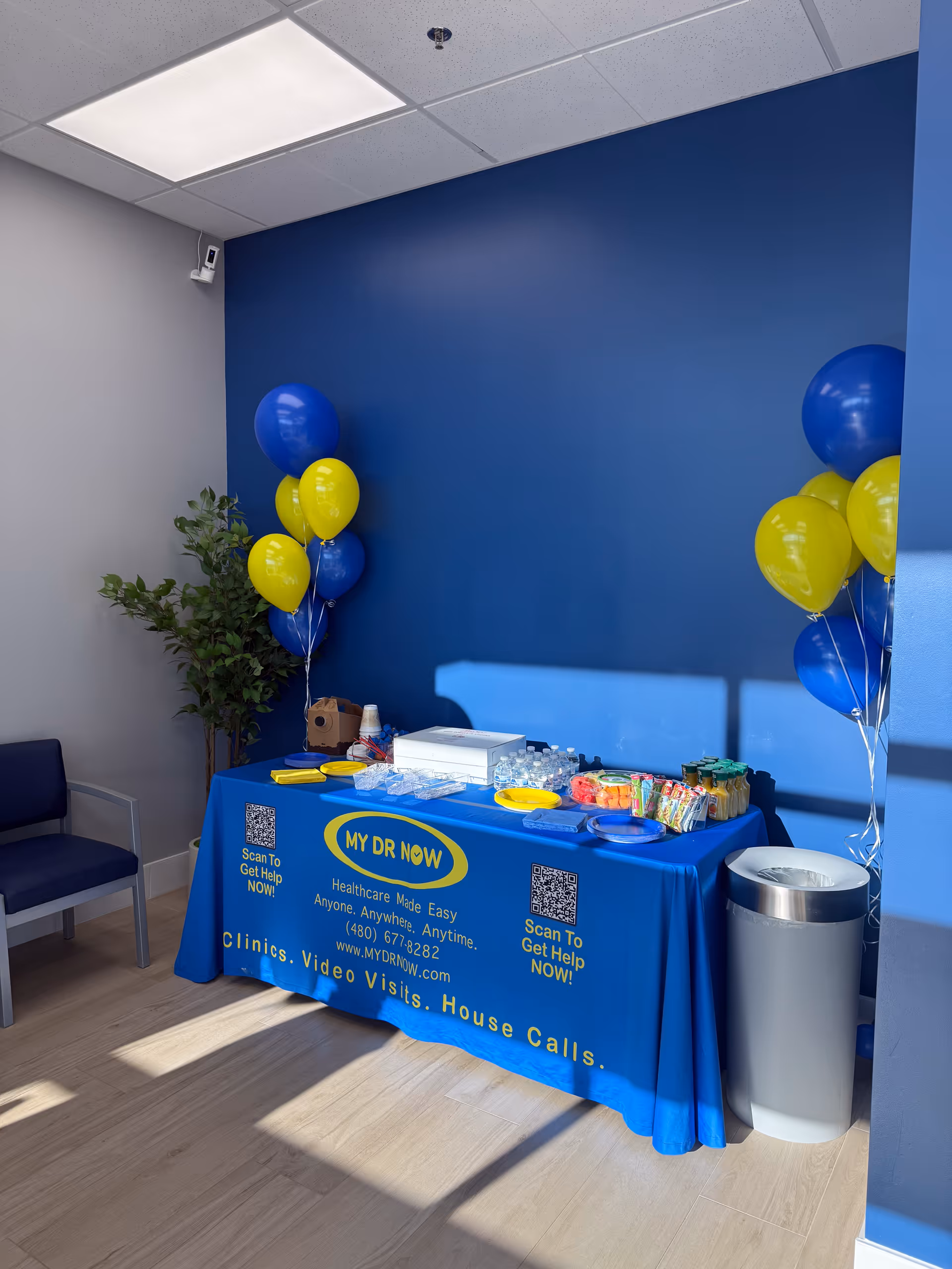 Indoor promotional table with MY DR NOW branding, balloons, and snacks.
