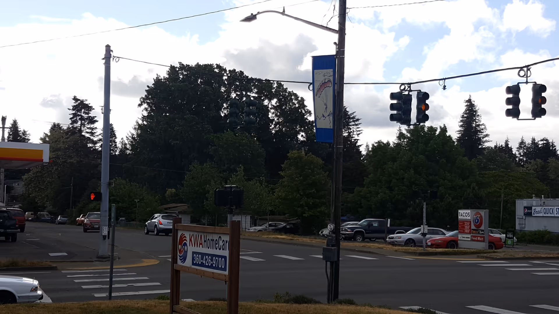 Busy street intersection with traffic lights and a KWA HomeCare sign near the facility.
