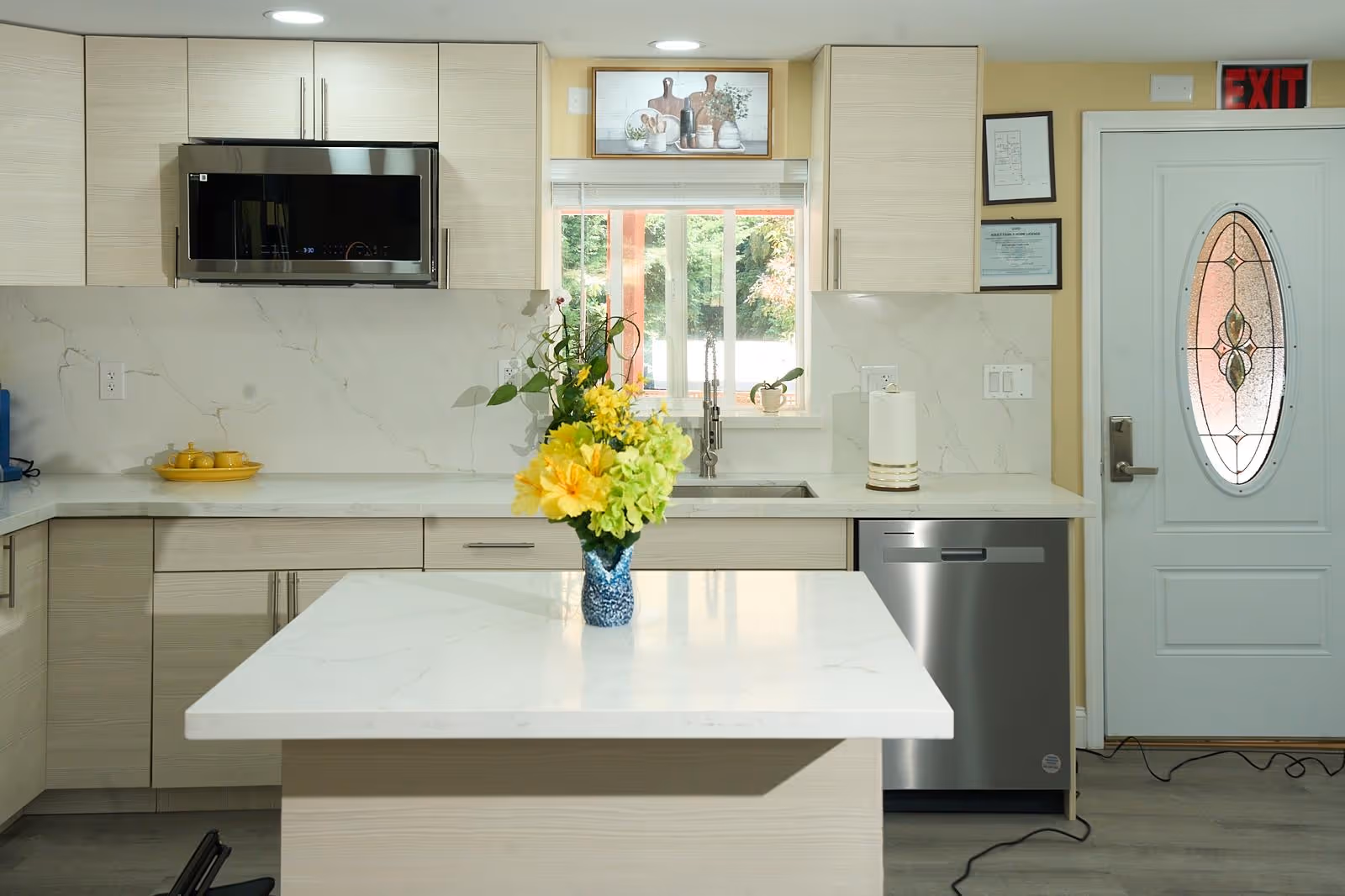 Bright, modern kitchen in a senior living facility with island, sink, and decorative glass door.