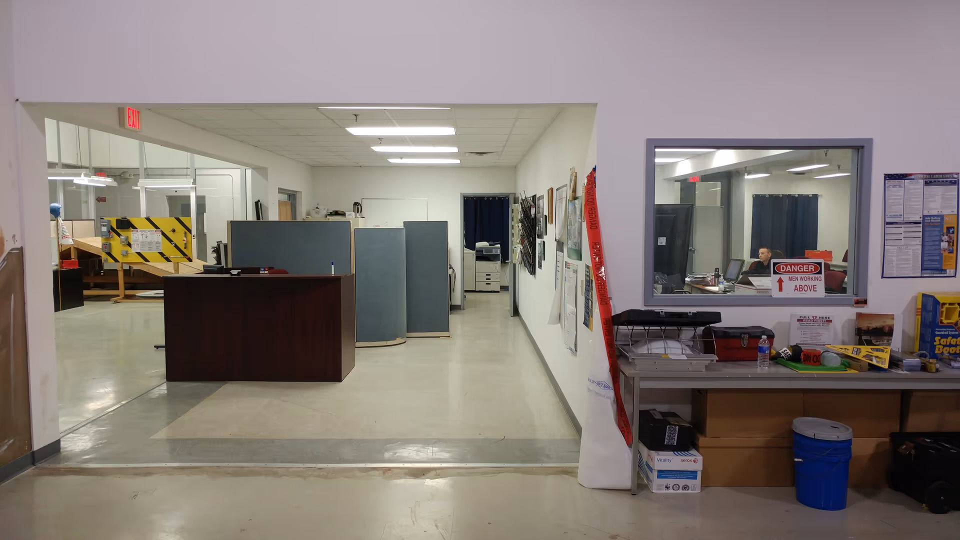 Open interior facility lobby with reception desk, cubicles, and a windowed office area.