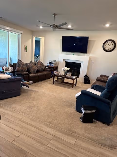 Cozy living room with couches, a fireplace, TV, and a wall clock.