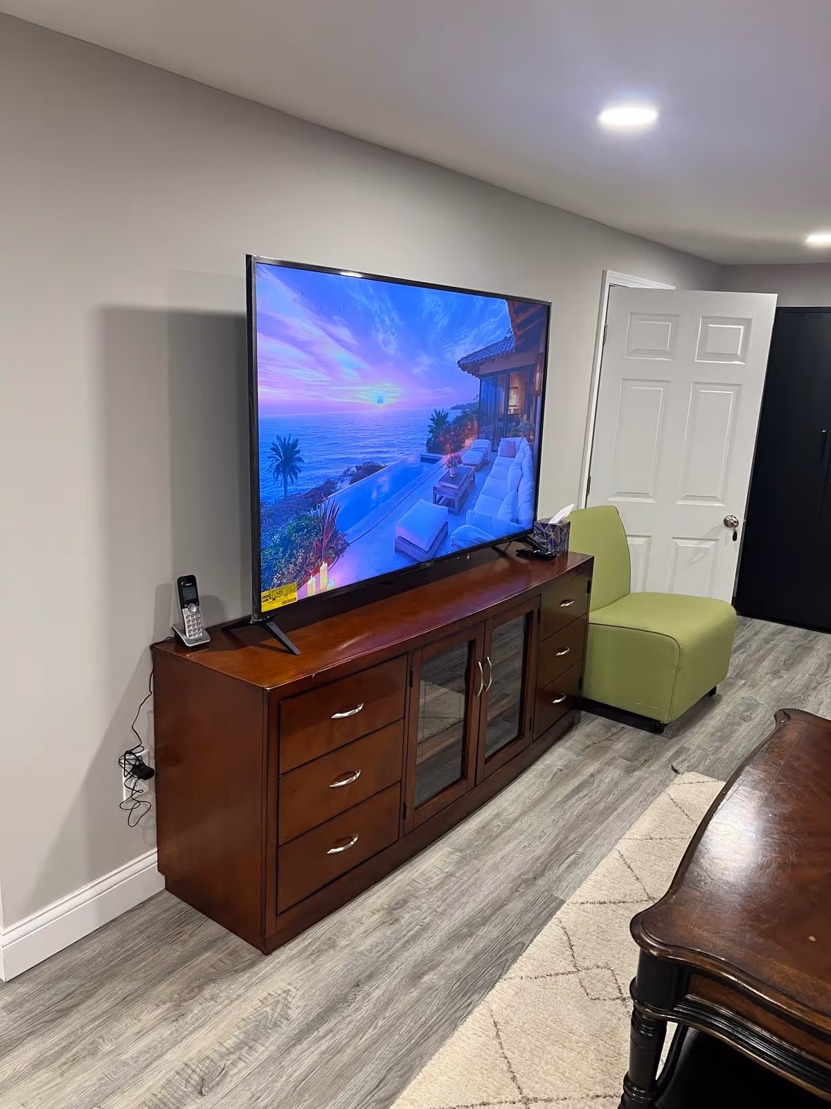 Living room with a large TV on a wooden console and a green chair.
