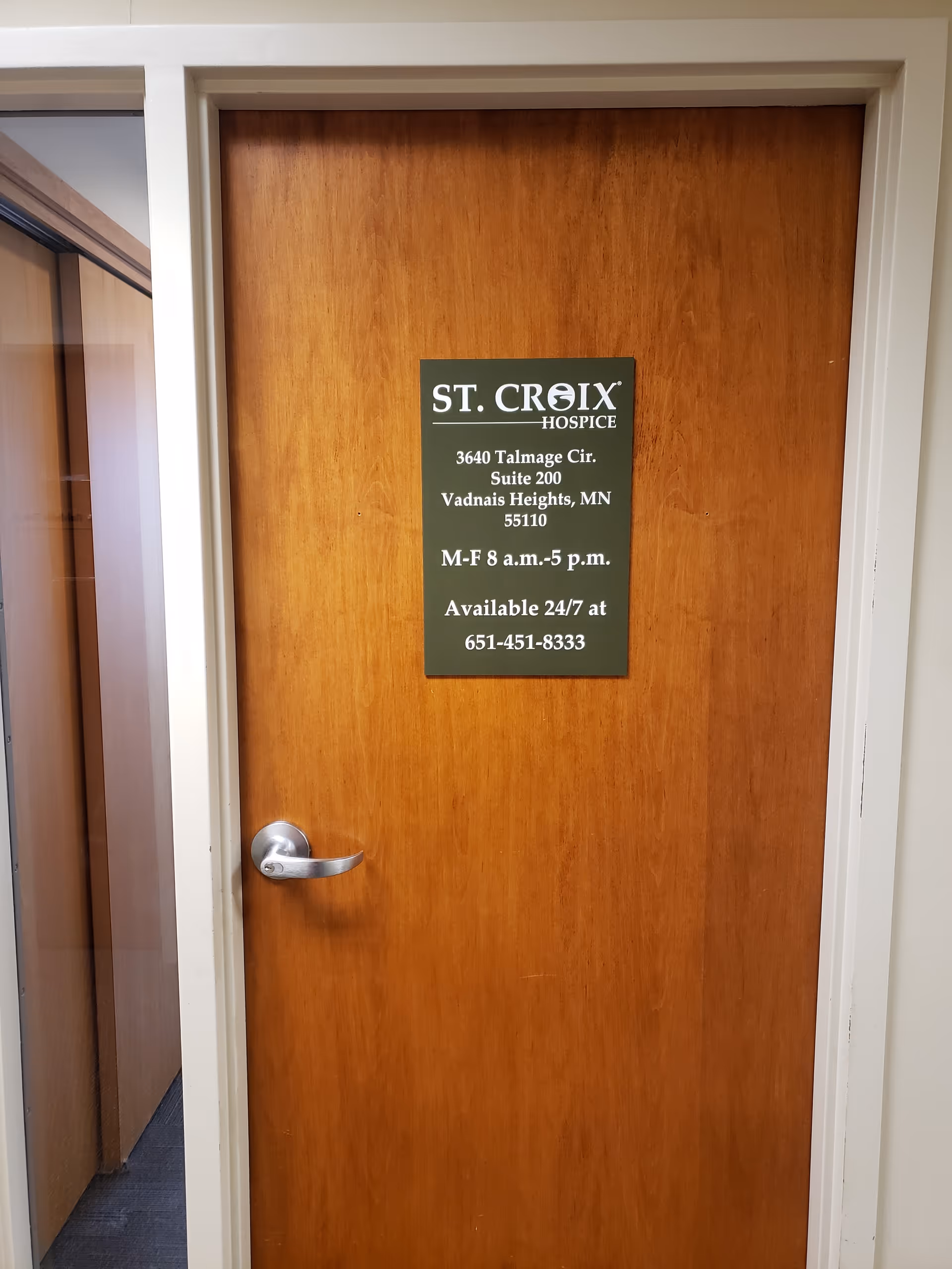 Interior wooden door with a green St. Croix Hospice sign attached.