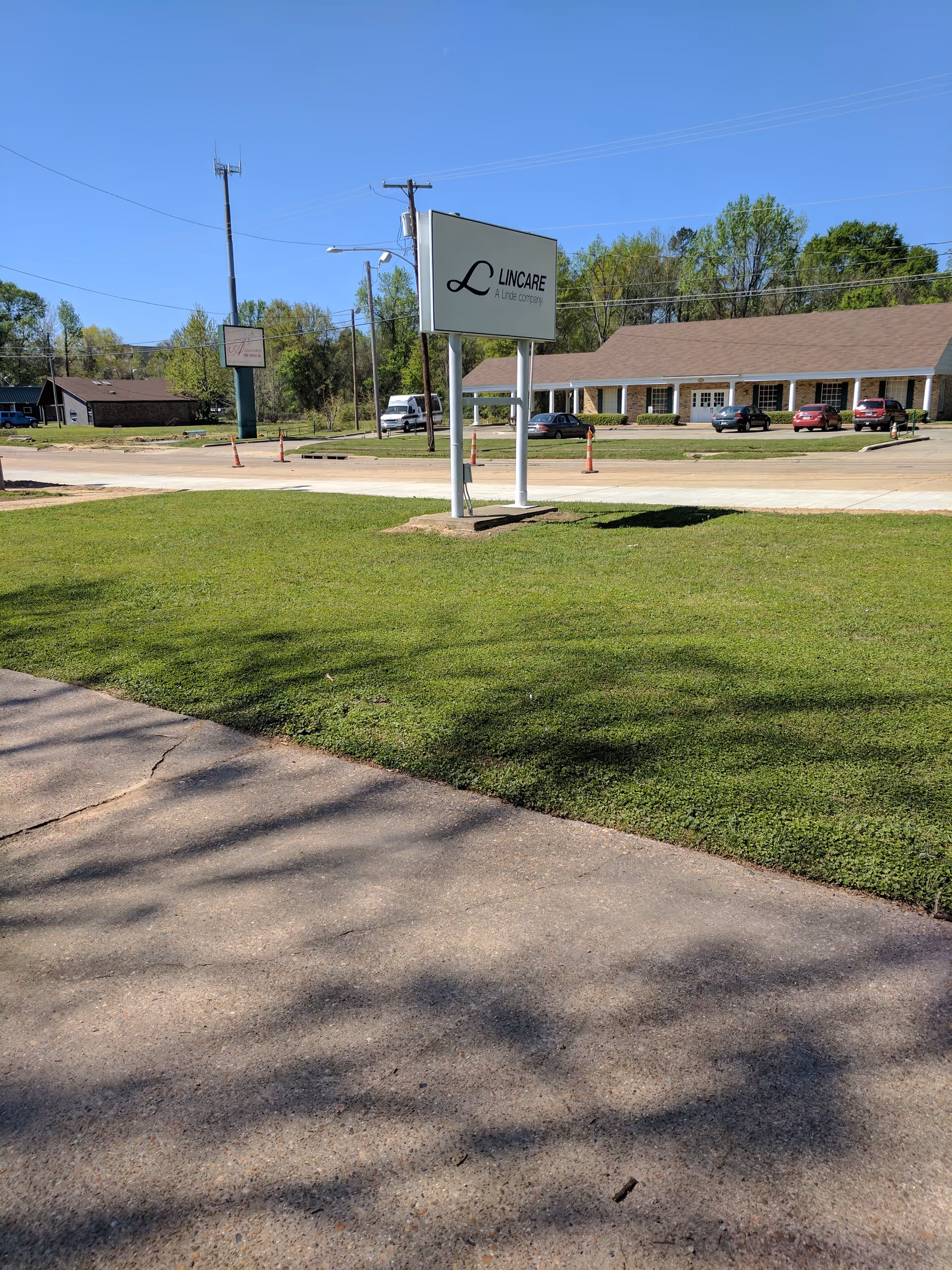 Exterior view of a LINCARE building with a prominent sign, parking lot, and green lawn.