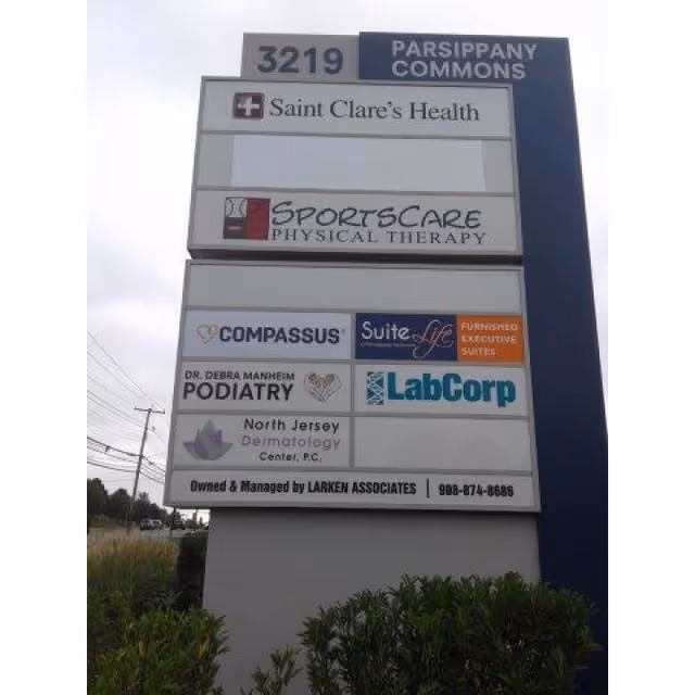 Tall outdoor sign displaying multiple company logos, including Compassus, Saint Clare's Health, and LabCorp