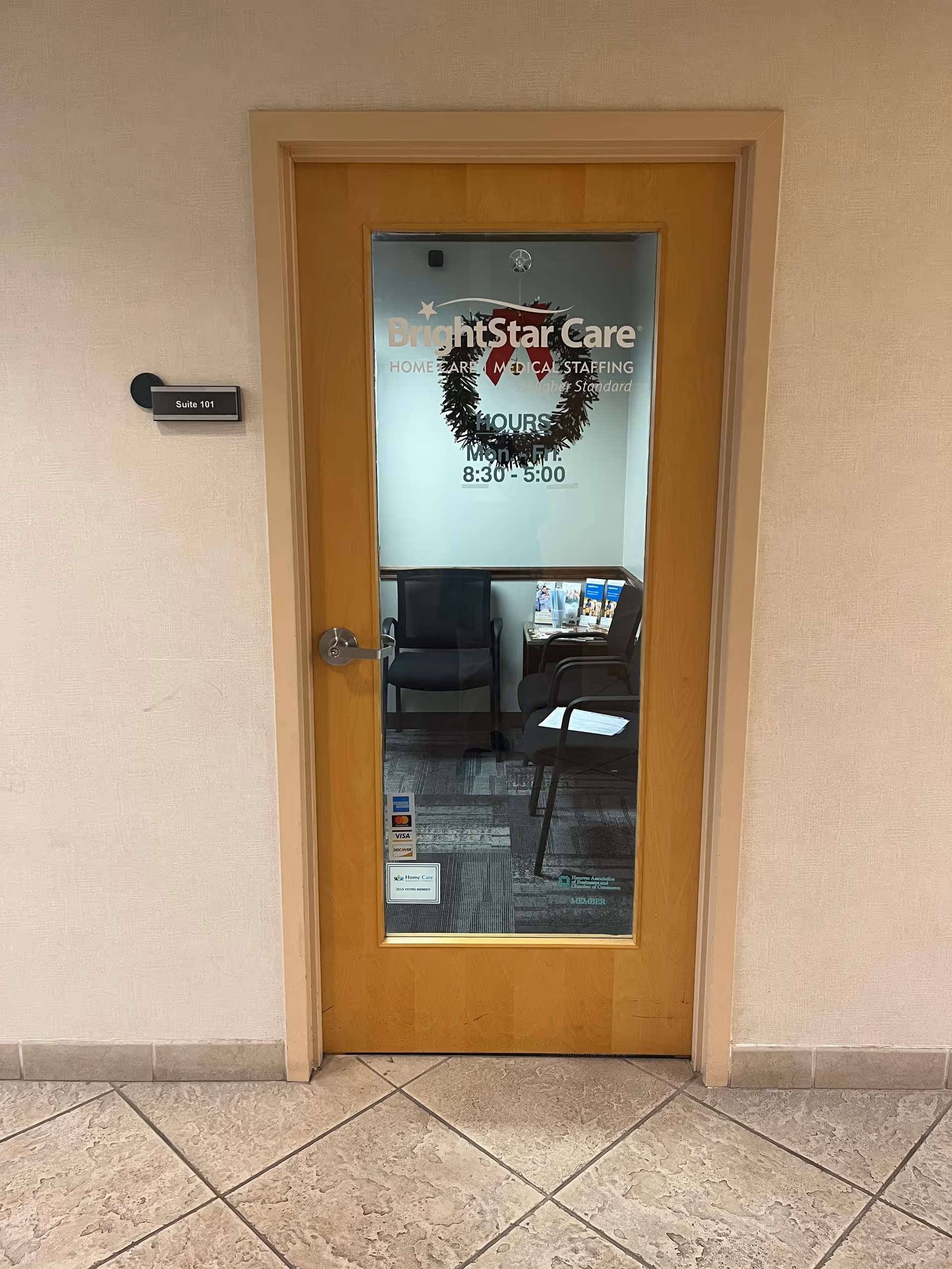 Wooden door with glass pane shows BrightStar Care logo; a small waiting area is visible beyond.