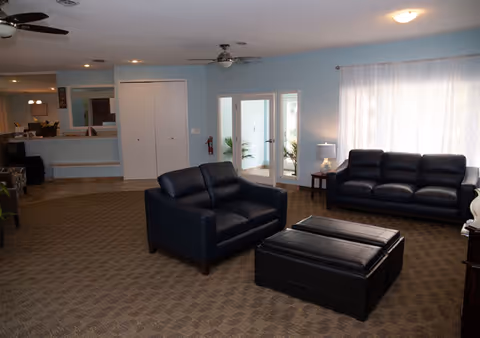 Spacious lounge area with black leather seating, ottoman, carpet, and soft lighting.