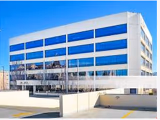 Modern blue-glass facility exterior with a ramp leading to the entrance.