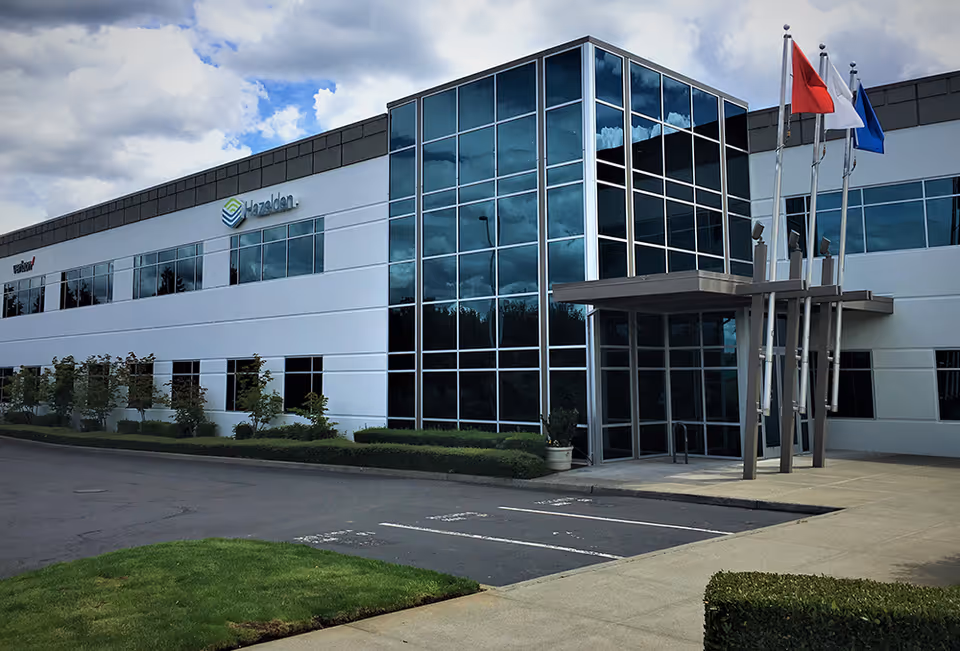 Modern office-style building with glass facade, flagpoles, and a covered entrance.