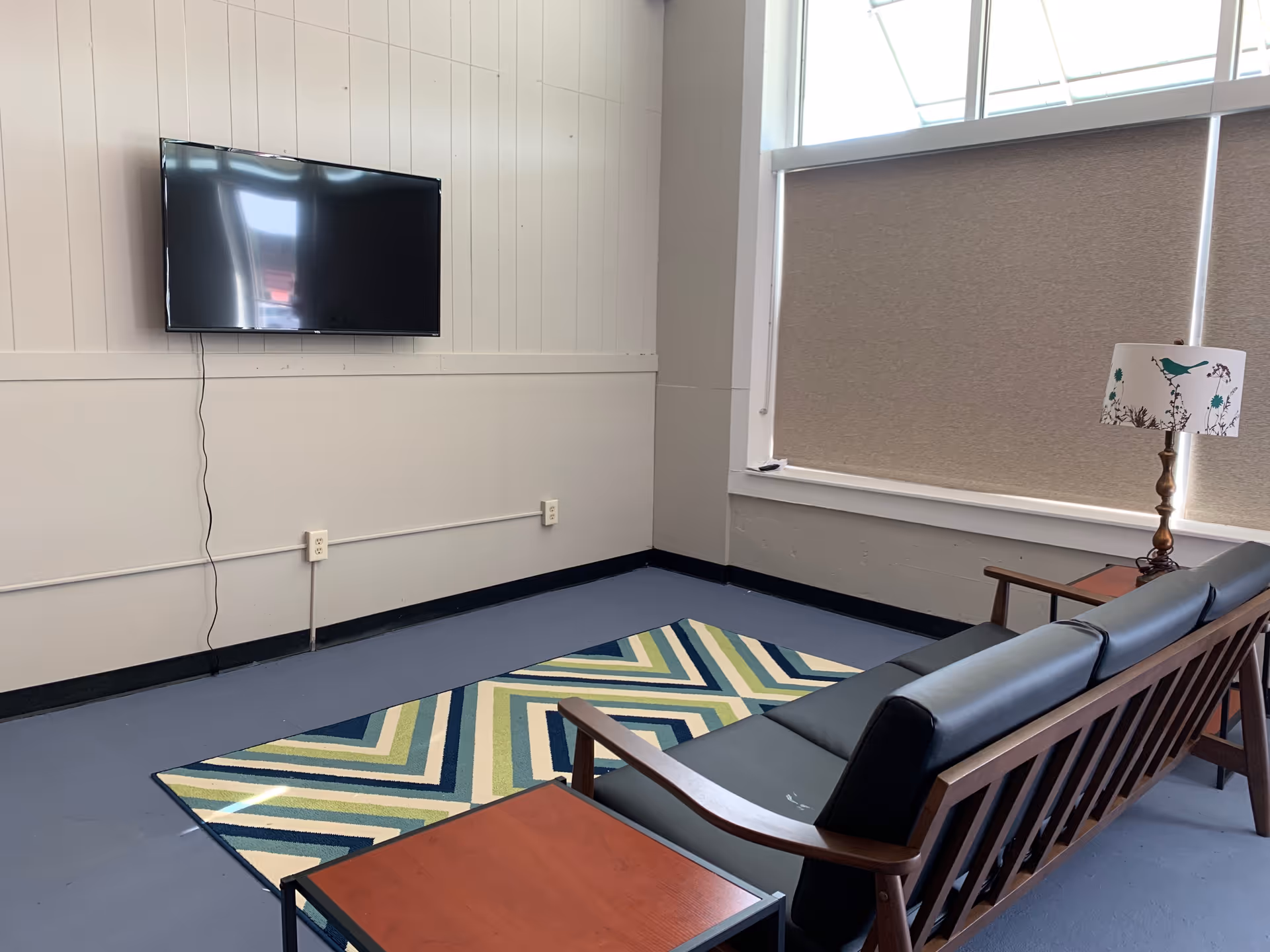 A modern living room lounge in a senior facility with TV and seating.