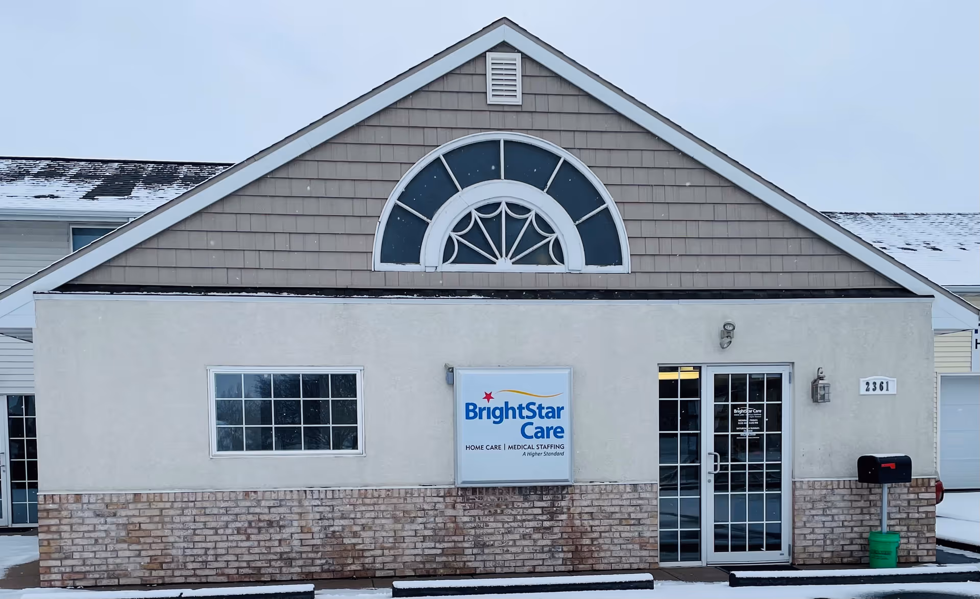 Front view of BrightStar Care facility, with sign, brick base, and glass entrance door.