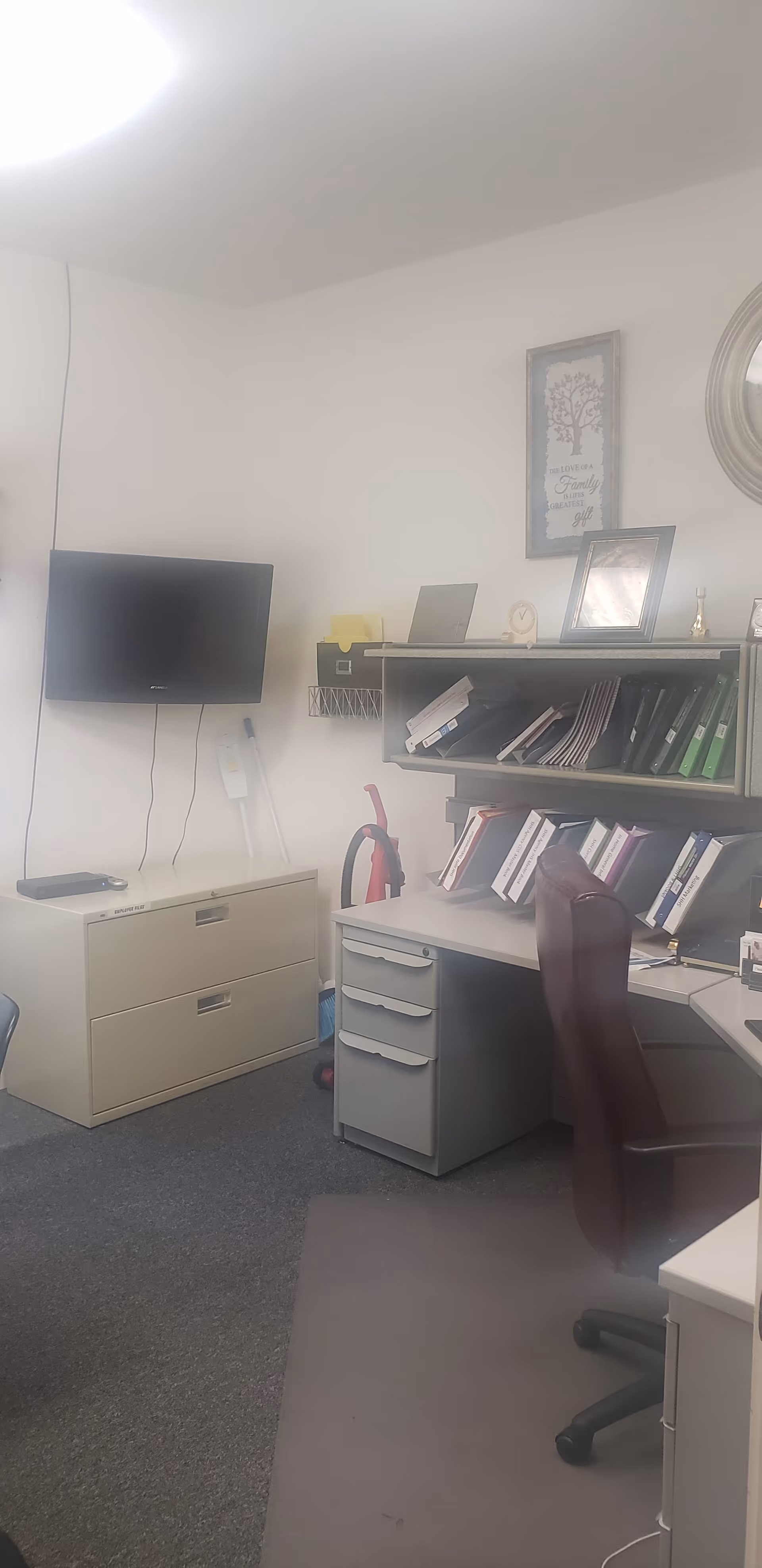 Office workspace in a senior facility with desk, filing cabinet, and shelves.