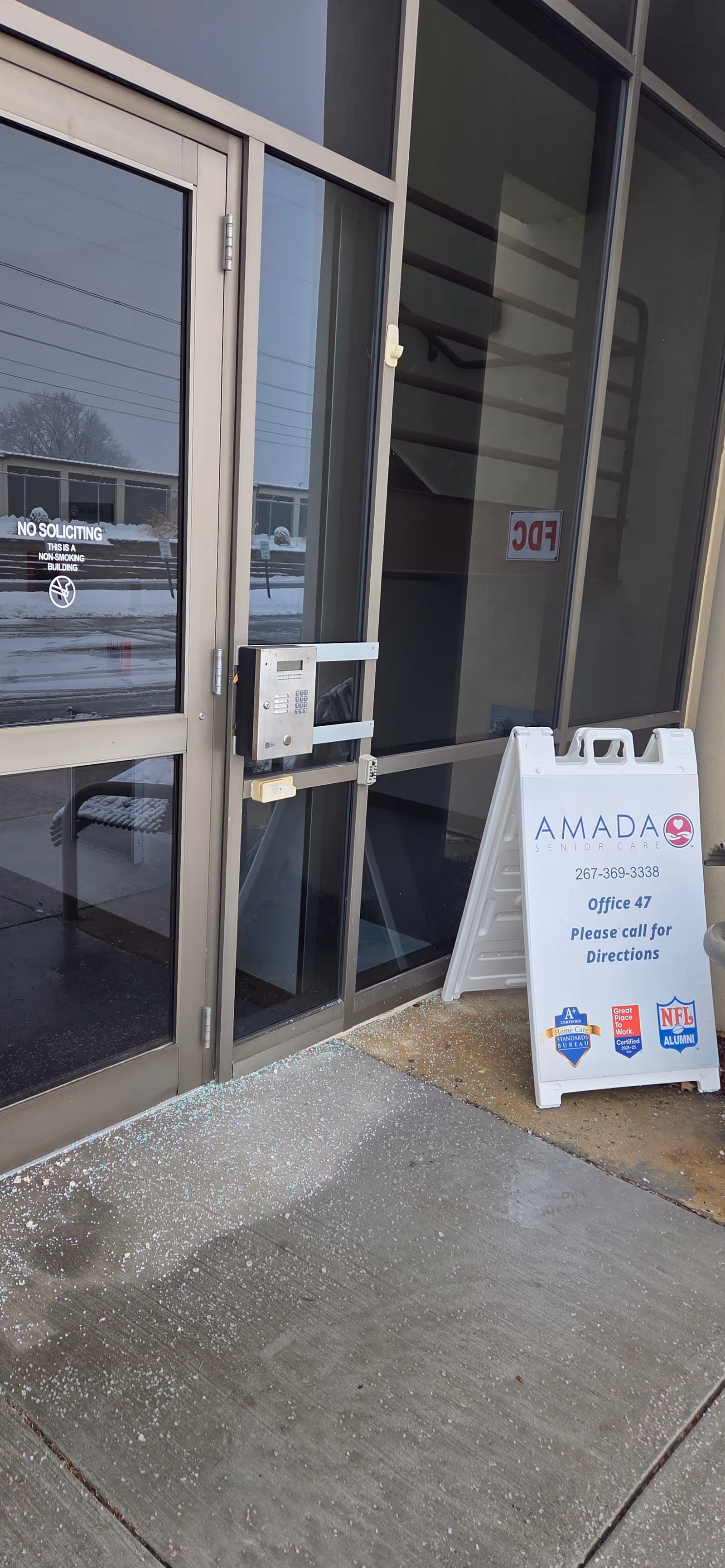 Front entrance of Amada Senior Care with glass doors and a sidewalk signboard.