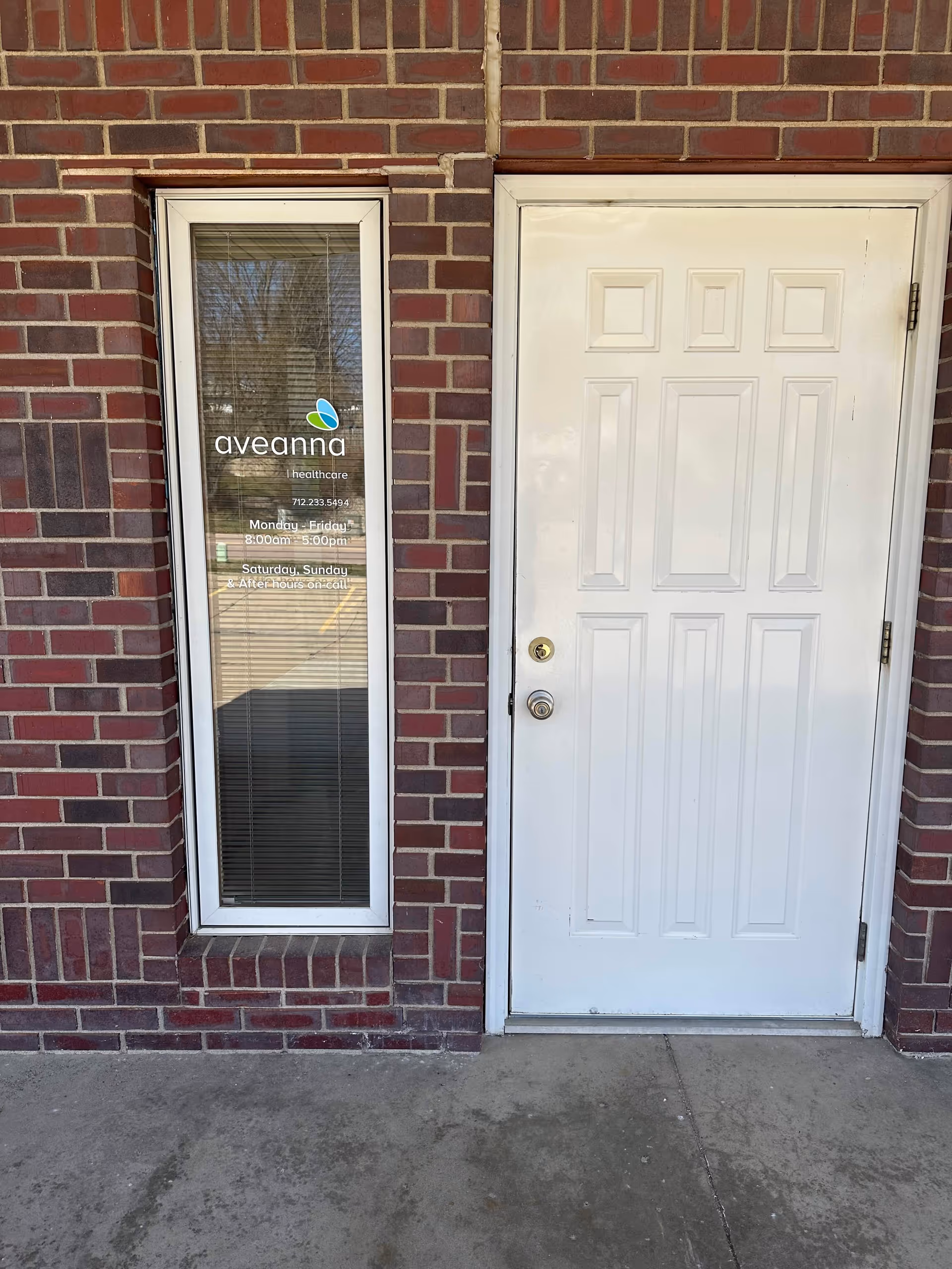 Brick exterior with a glass door bearing Aveanna logo beside a white entry door.