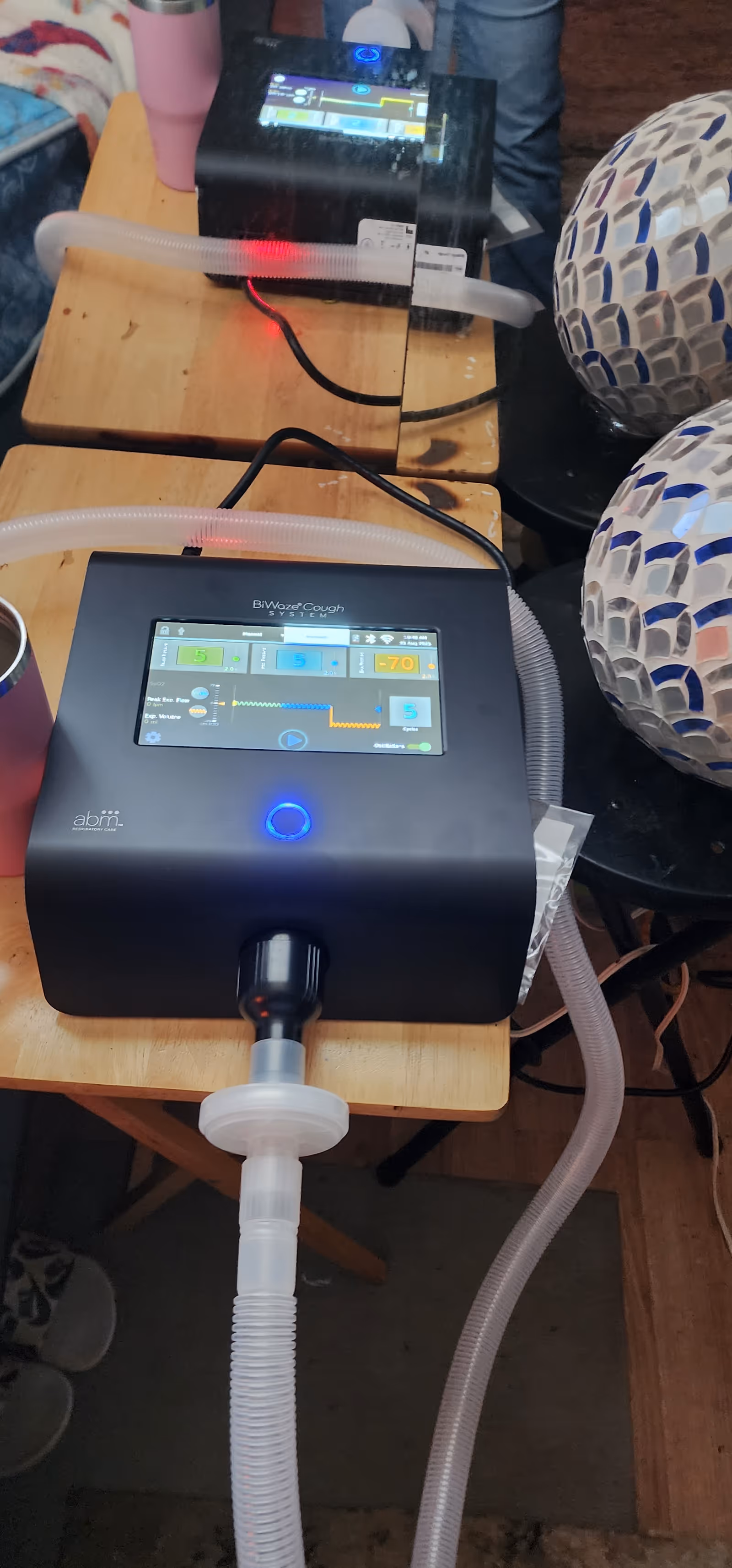 Oxygen therapy machine with tubing and mosaic-patterned exercise balls on a wooden table.