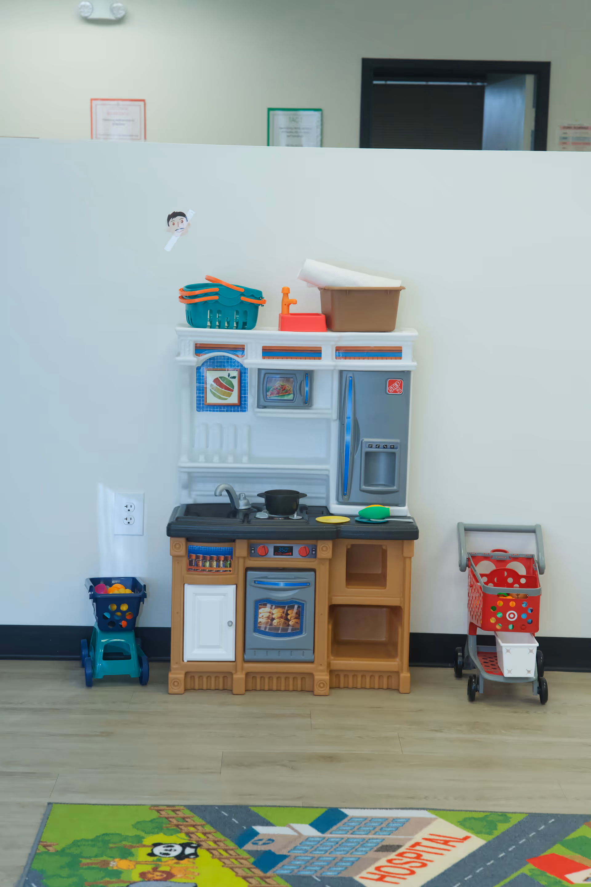 Colorful children's toy kitchen set against a pale wall in a play area.
