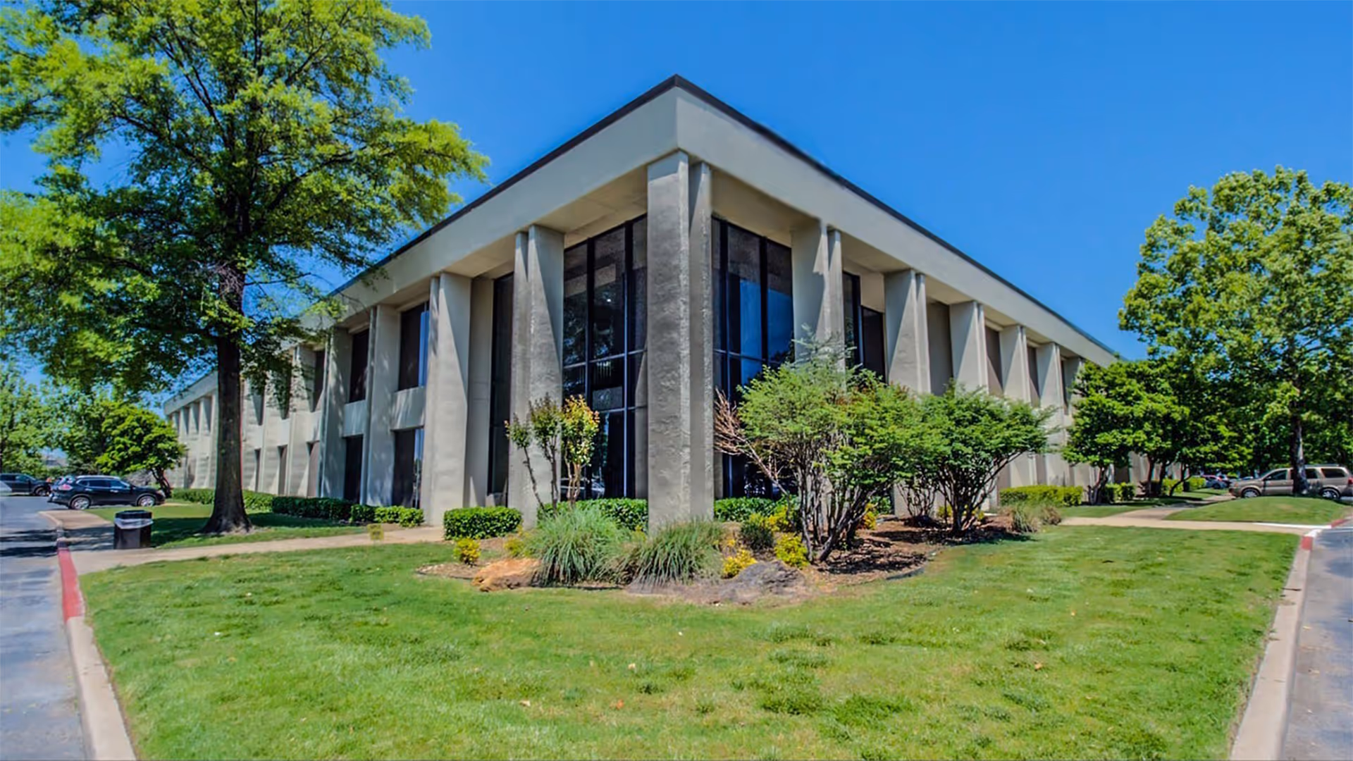 Exterior view of a modern senior living facility with glass windows and manicured landscaping.