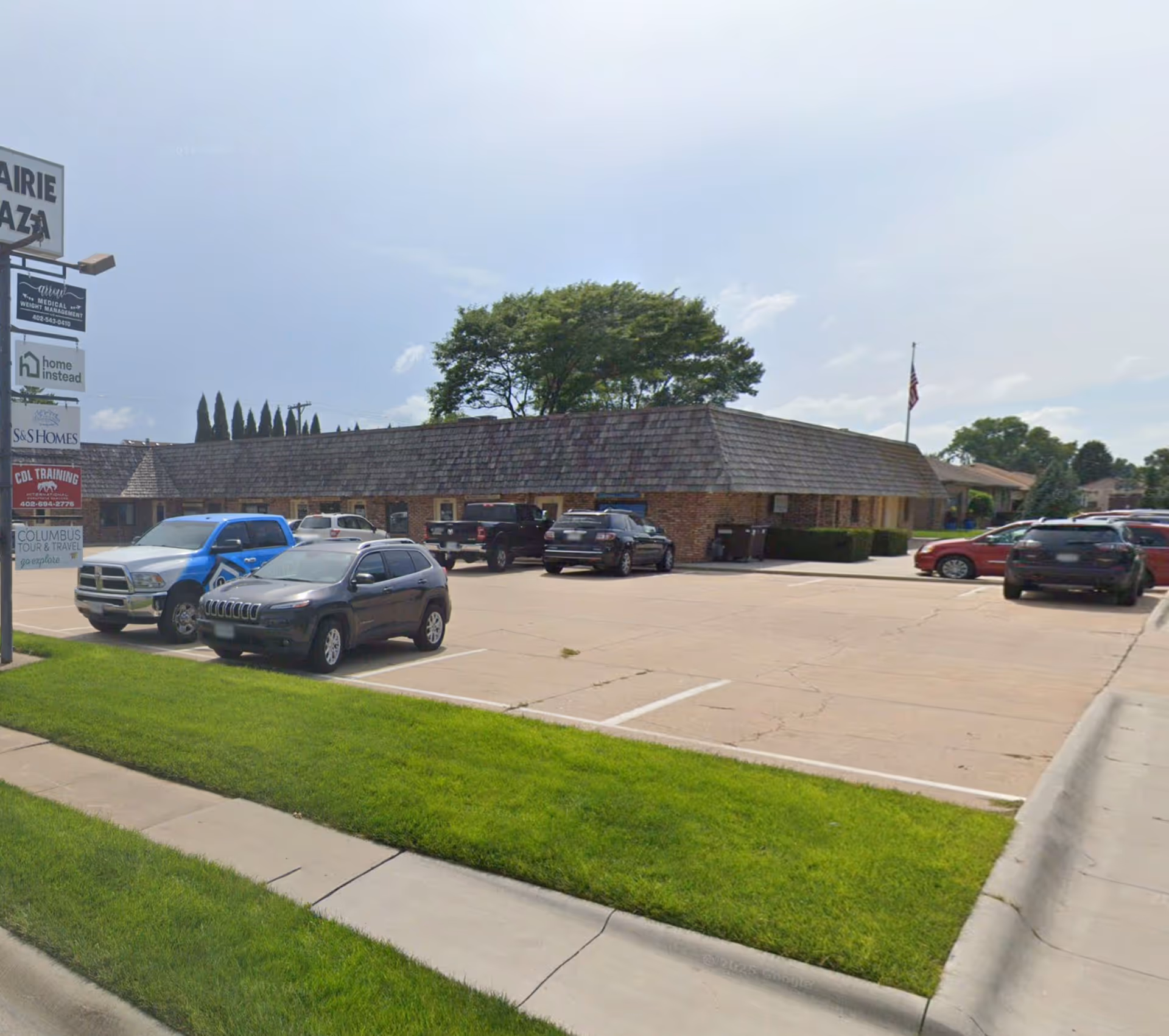 Single-story brick building with a parking lot and a tall sign reading Home Instead.