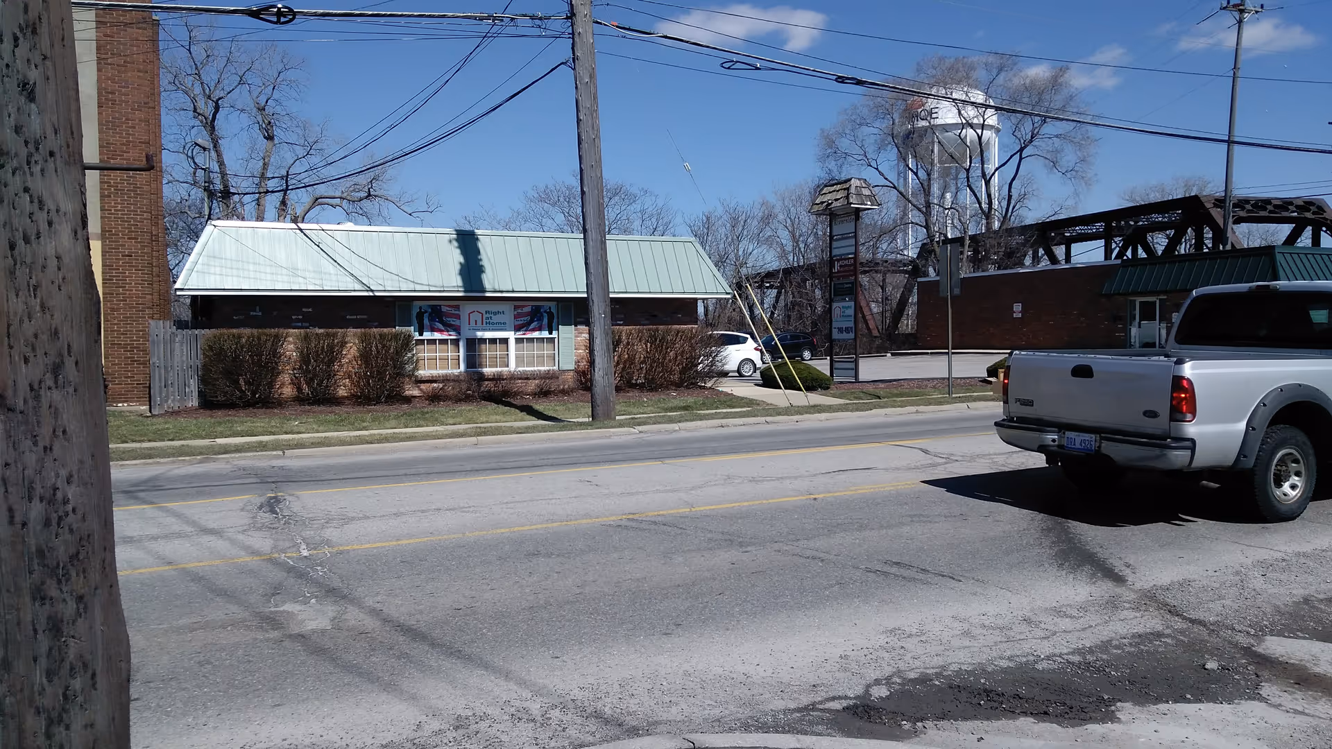 Exterior view of a Right at Home facility along a street with a white pickup.