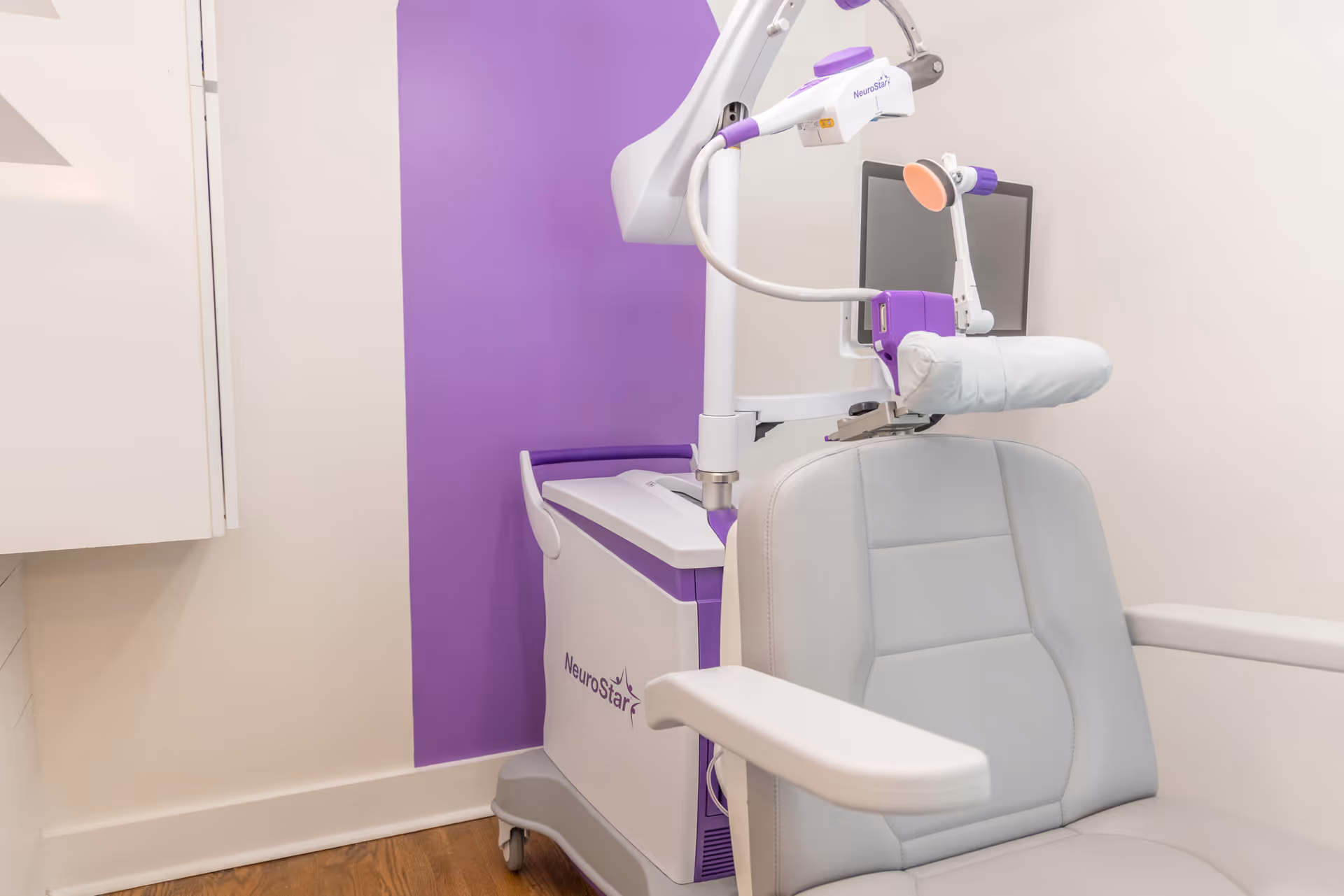 Treatment chair beside a NeuroStar machine with purple accents in a clean interior.