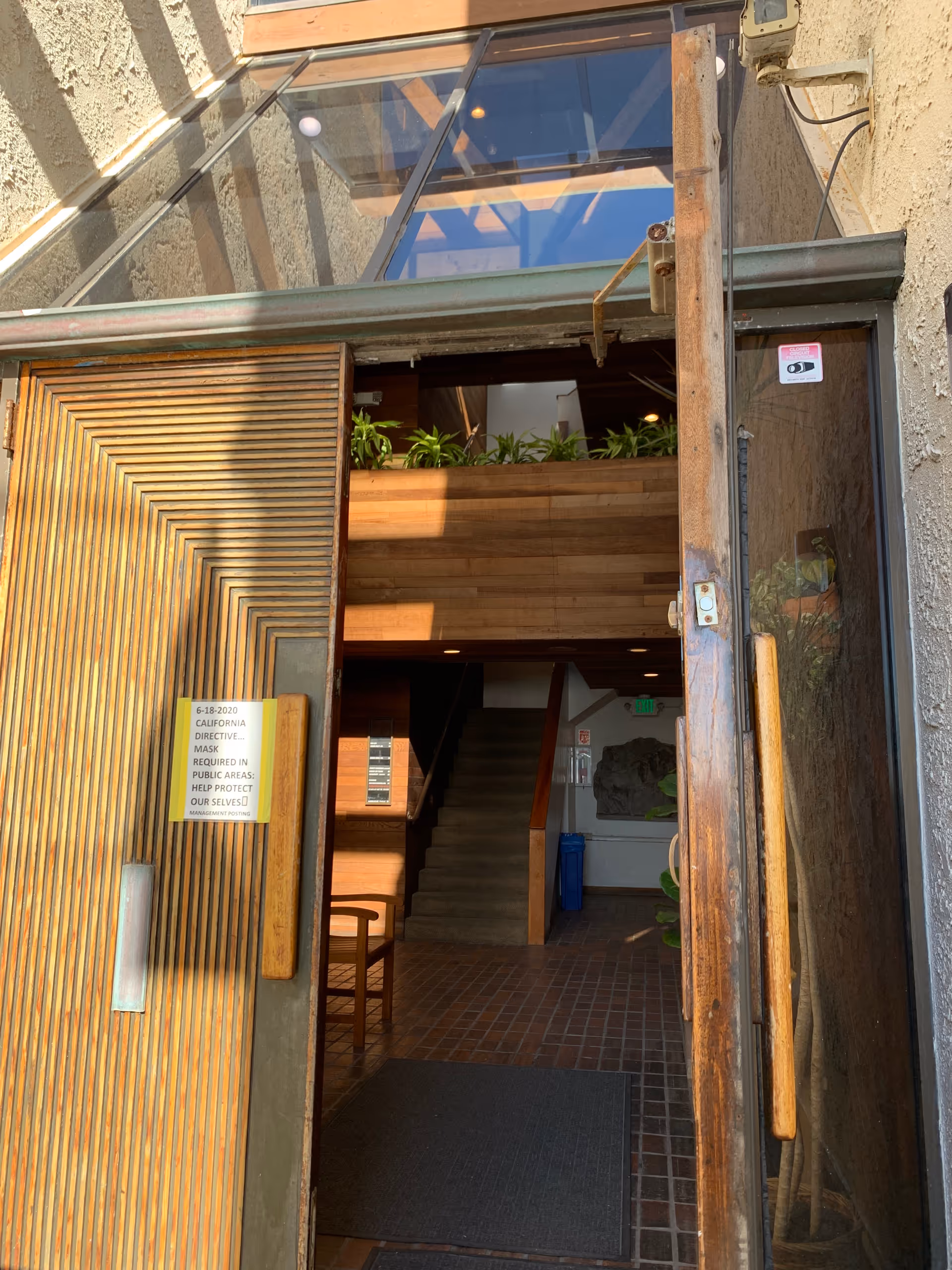 SYNERGY HomeCare lobby entrance with wooden doors, stairs, and potted plants.