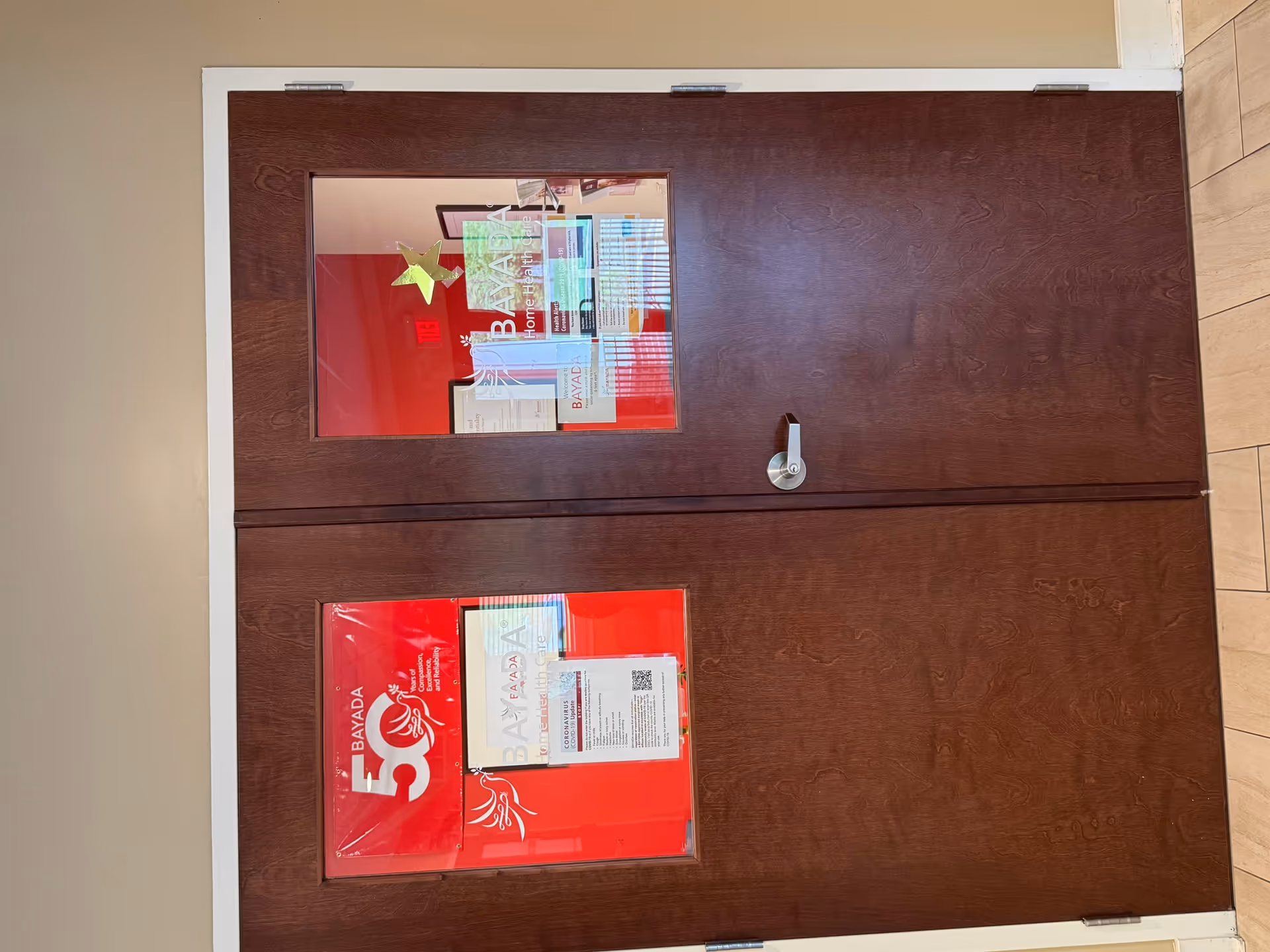 Interior double brown doors with glass panels displaying BAYADA Home Health signage and papers.
