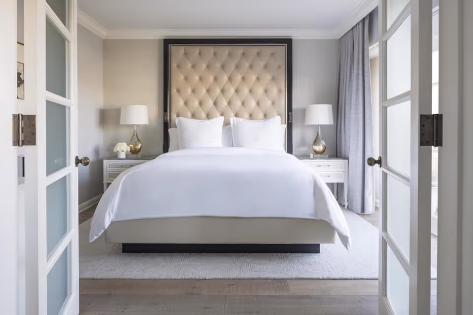Bright bedroom with a large bed, tufted headboard, nightstands, and two lamps.