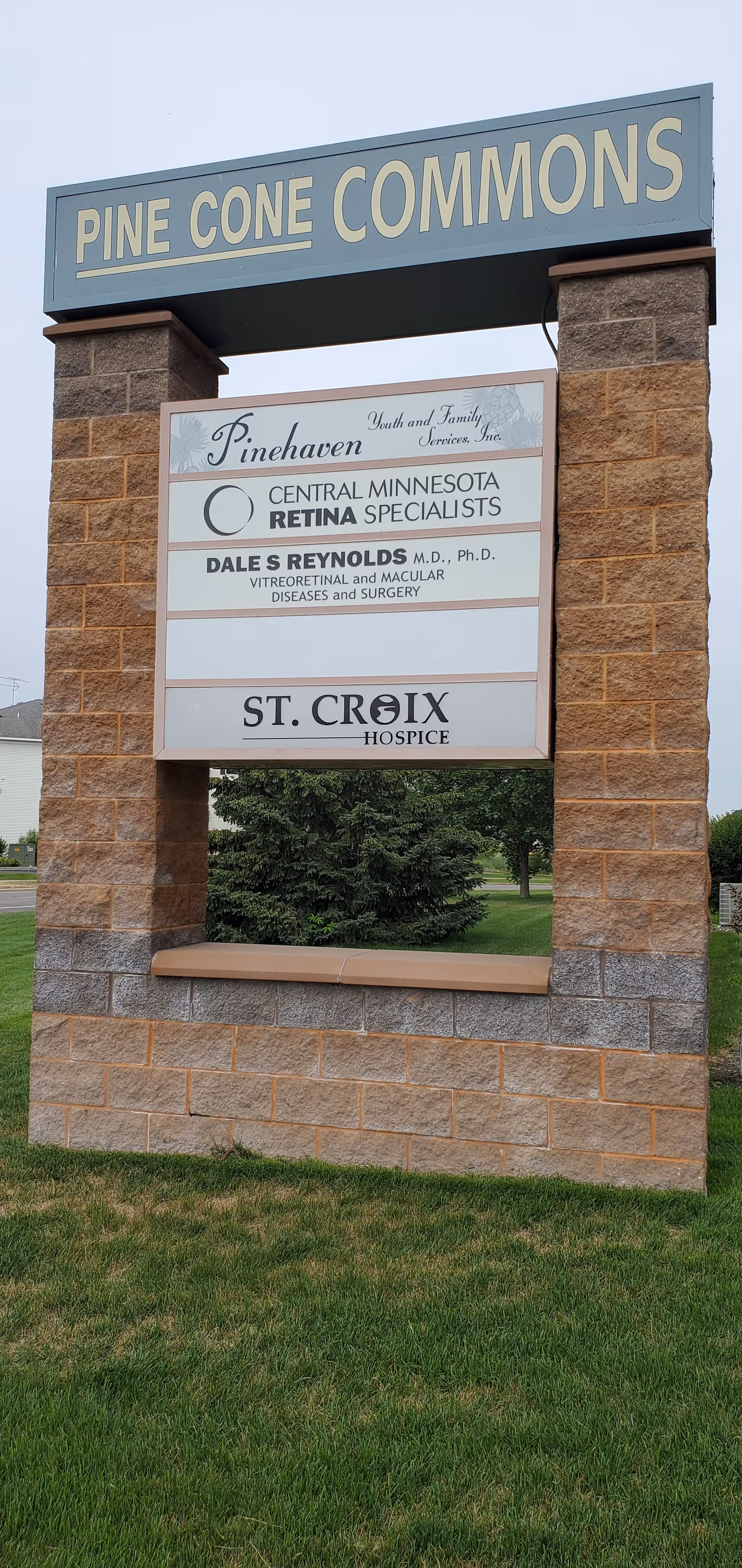 Exterior stone sign for Pine Cone Commons with St. Croix Hospice signage.
