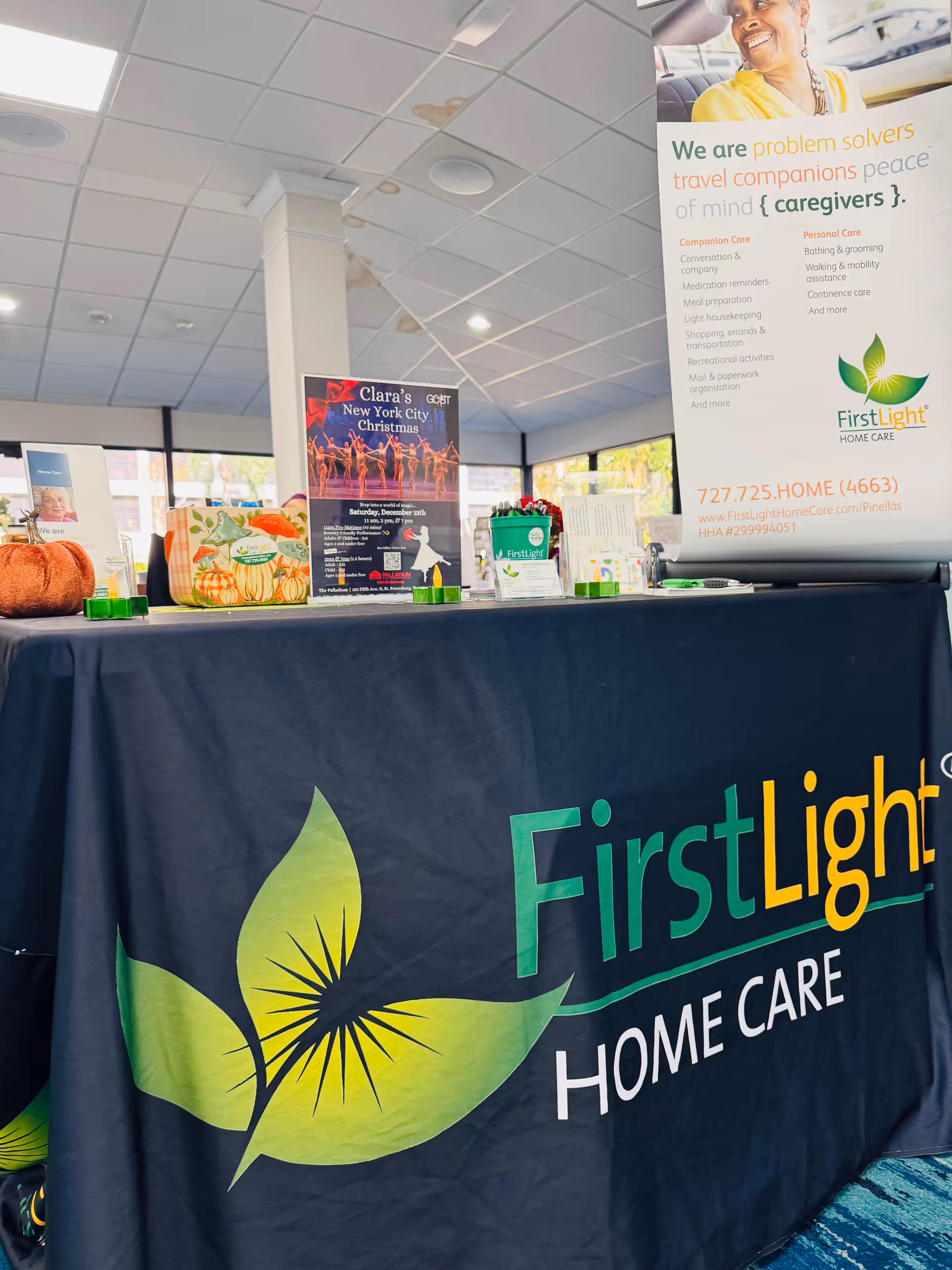 Indoor reception area with a FirstLight Home Care banner and promotional table display.