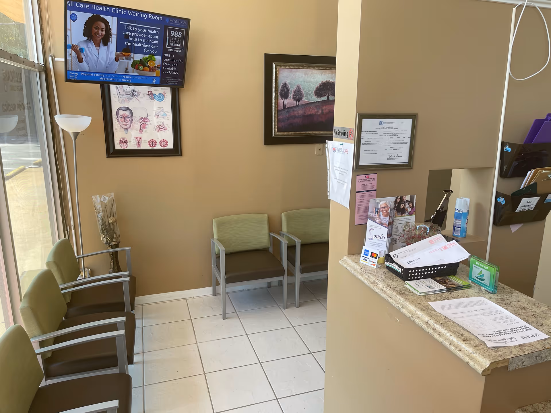 Clinic waiting area with green and brown chairs, a reception desk, and wall art.