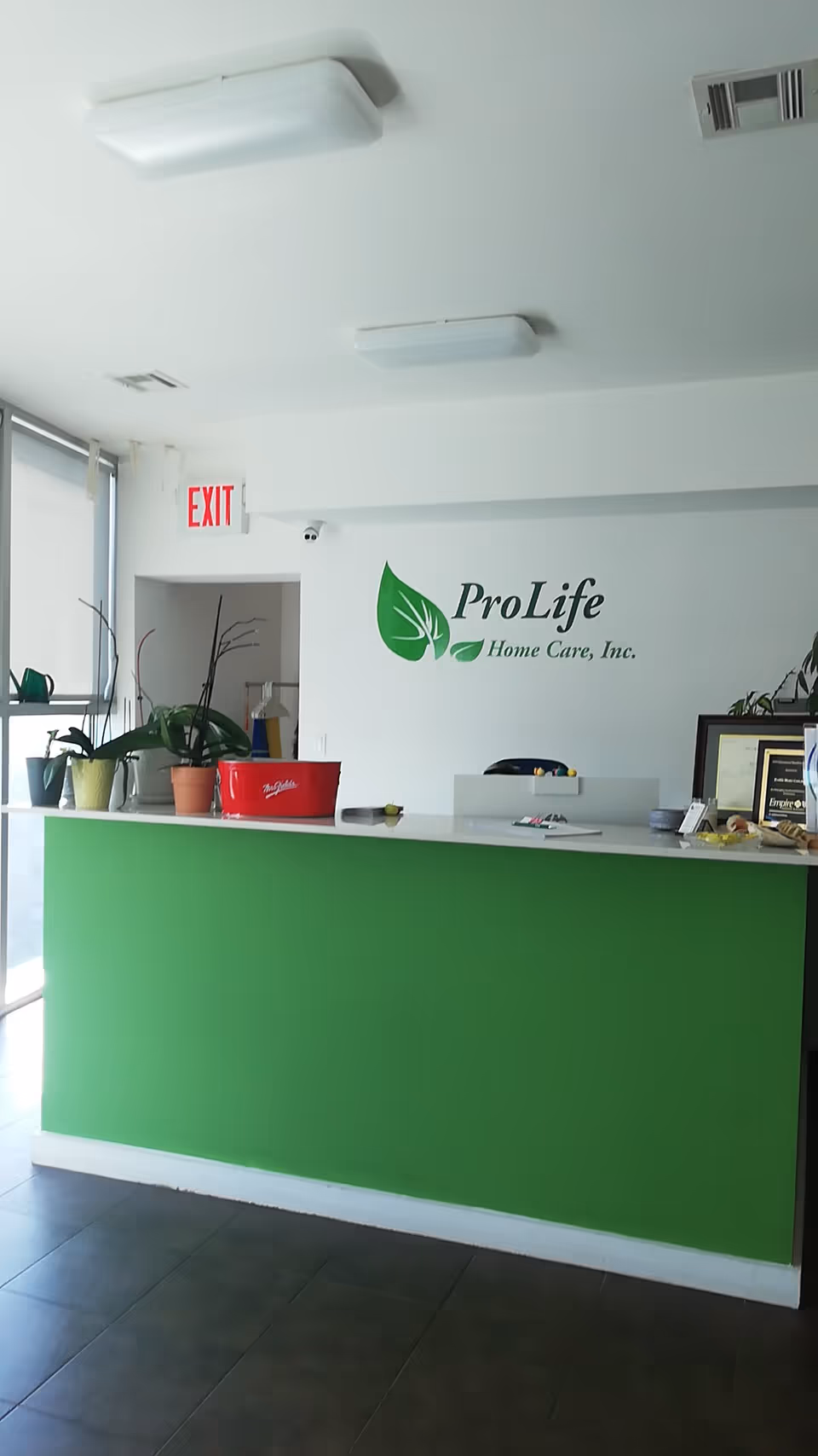 Interior reception area with a green-front desk and ProLife Home Care logo.