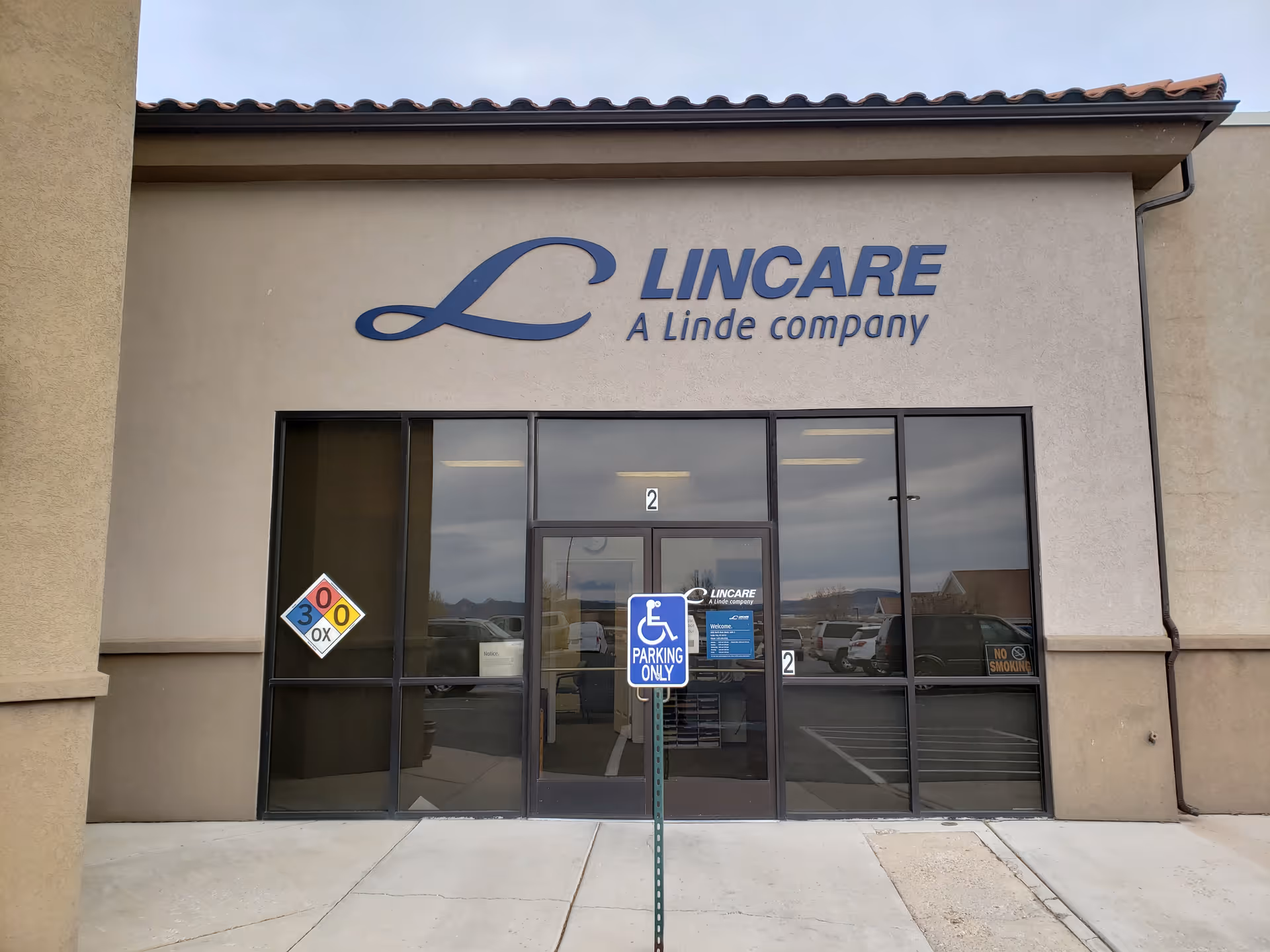Front exterior of a LINCARE facility with glass doors and handicap parking sign