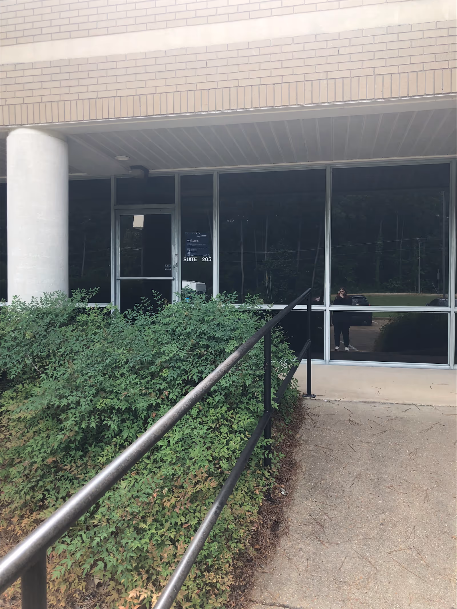 Exterior view of LINCARE INC. facility entrance with glass doors and landscaped greenery.