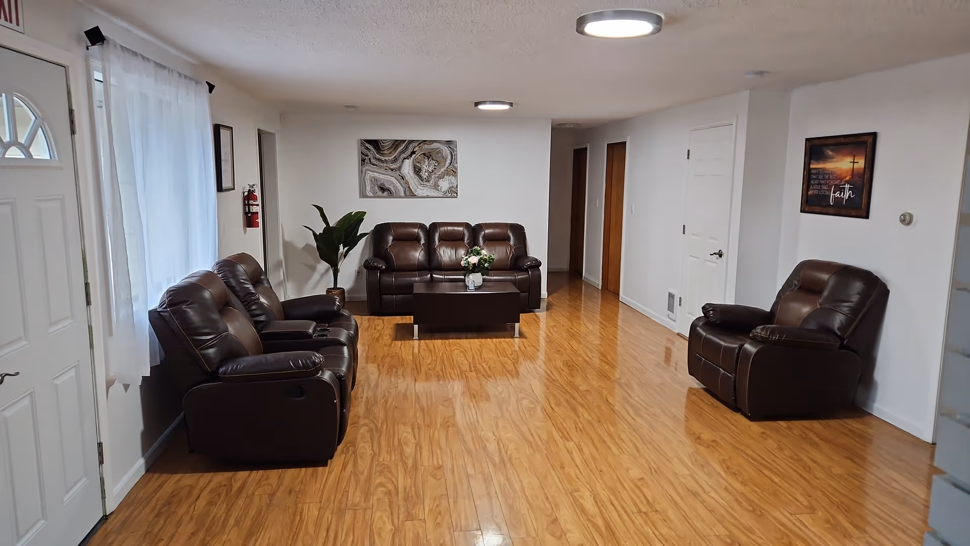 Spacious living area with brown leather sofas, a coffee table, plants, and wall art.