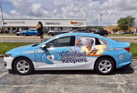 Blue Comfort Keepers car with logo parked in a lot.