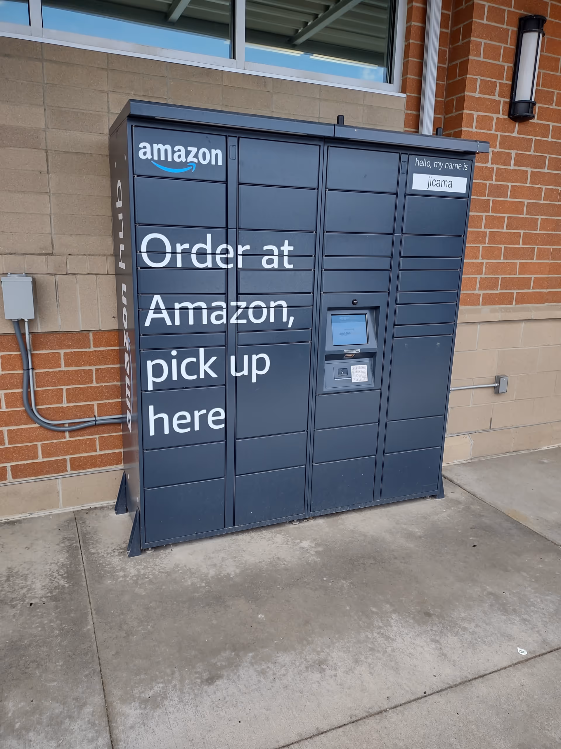 A large blue Amazon pickup locker outside a brick building.