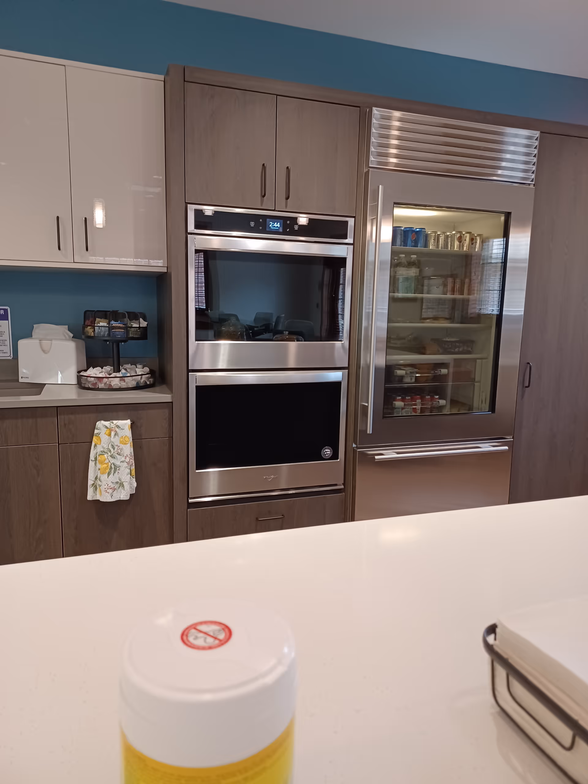 Modern kitchen with a double oven, wine fridge, and white countertop.